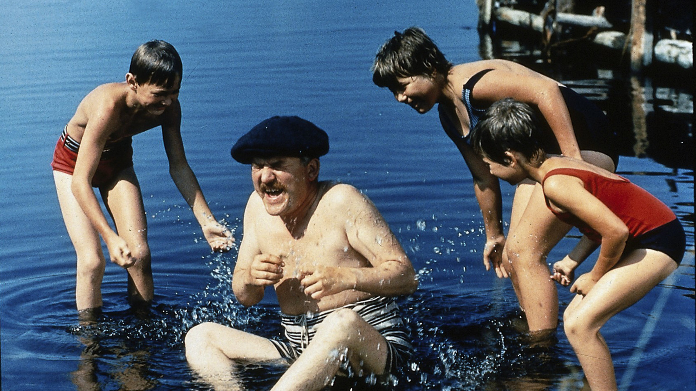 "Ferien auf Saltkrokan - Glückliche Heimkehr": Rüpel (Hans Alfredson) sitzt im Wasser. Er ist umringt von Pelle (Stephen Lindholm), Tjorven (Maria Johansson) und Stina (Christina Jämtmark), die ihn nass spritzen.