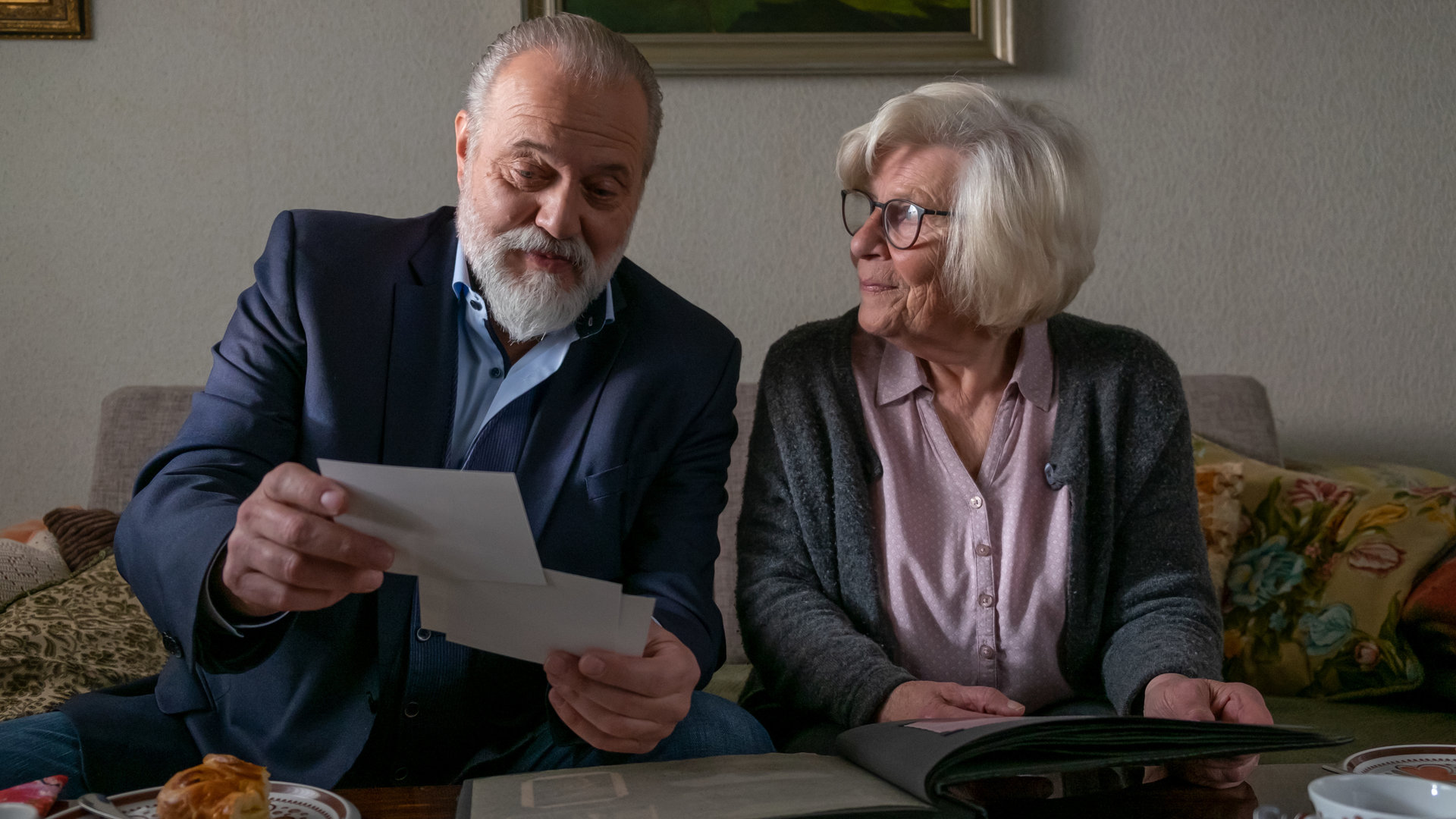"Der Alte - Ein Tag im Leben": Richard Voss (Jan-Gregor Kremp) sitzt neben der älteren Dame Frau Buteke (Christiane Blumhoff) dem Sofa. Sie schauen sich gemeinsam ein Fotoalbum an.