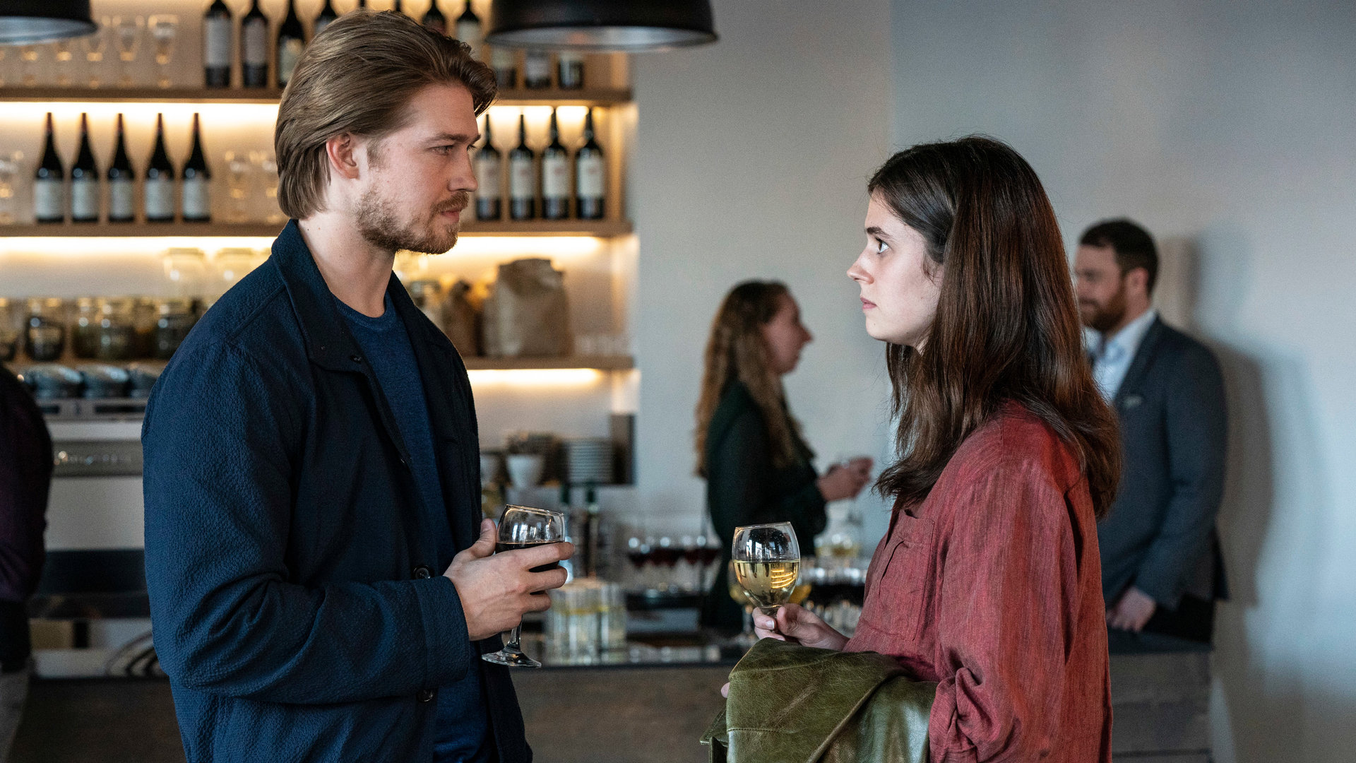 "Conversations with Friends - Spiel mit dem Feuer": Frances (Alison Oliver) und Nick (Joe Alwyn) stehen sich vor einer Bar gegenüber und schauen sich aufrichtig an, während sie jeweils ihren Drink in den Händen halten.