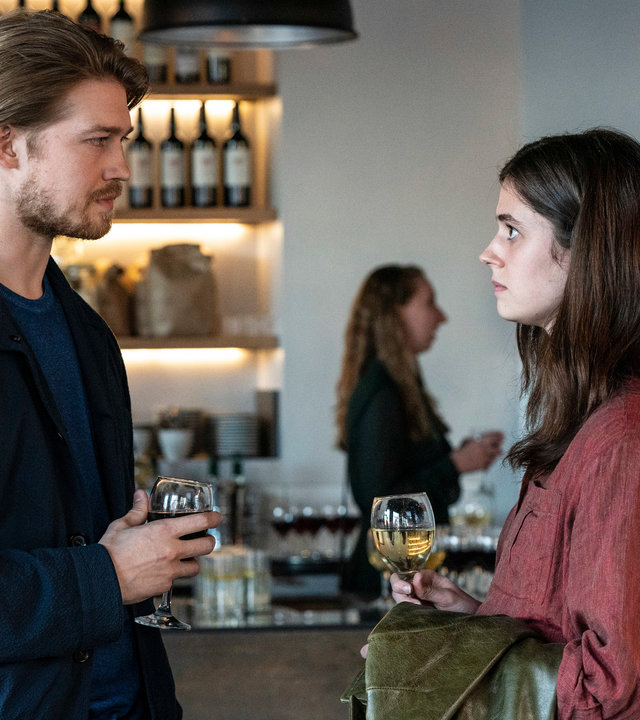 "Conversations with Friends - Spiel mit dem Feuer": Frances (Alison Oliver) und Nick (Joe Alwyn) stehen sich vor einer Bar gegenüber und schauen sich aufrichtig an, während sie jeweils ihren Drink in den Händen halten.