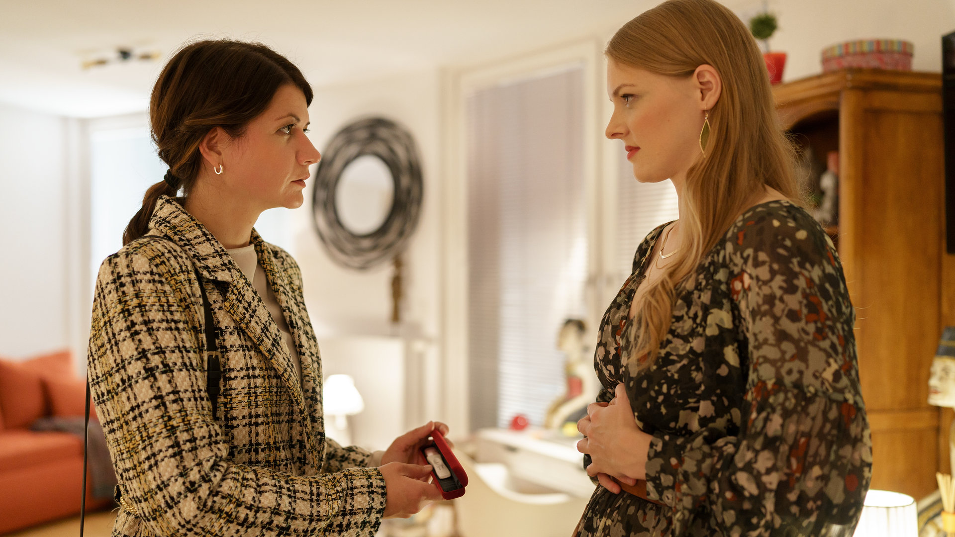 "SOKO Wien - Nur eine Nacht": In einem Wohnzimmer stehen sich Dr. Valentina Winter (Julia Rosa Peer) und Luise Haas (Annalena Kubinger) gegenüber. Dr. Valentina Winter hält einen Schwangerschaftstest in den Händen.