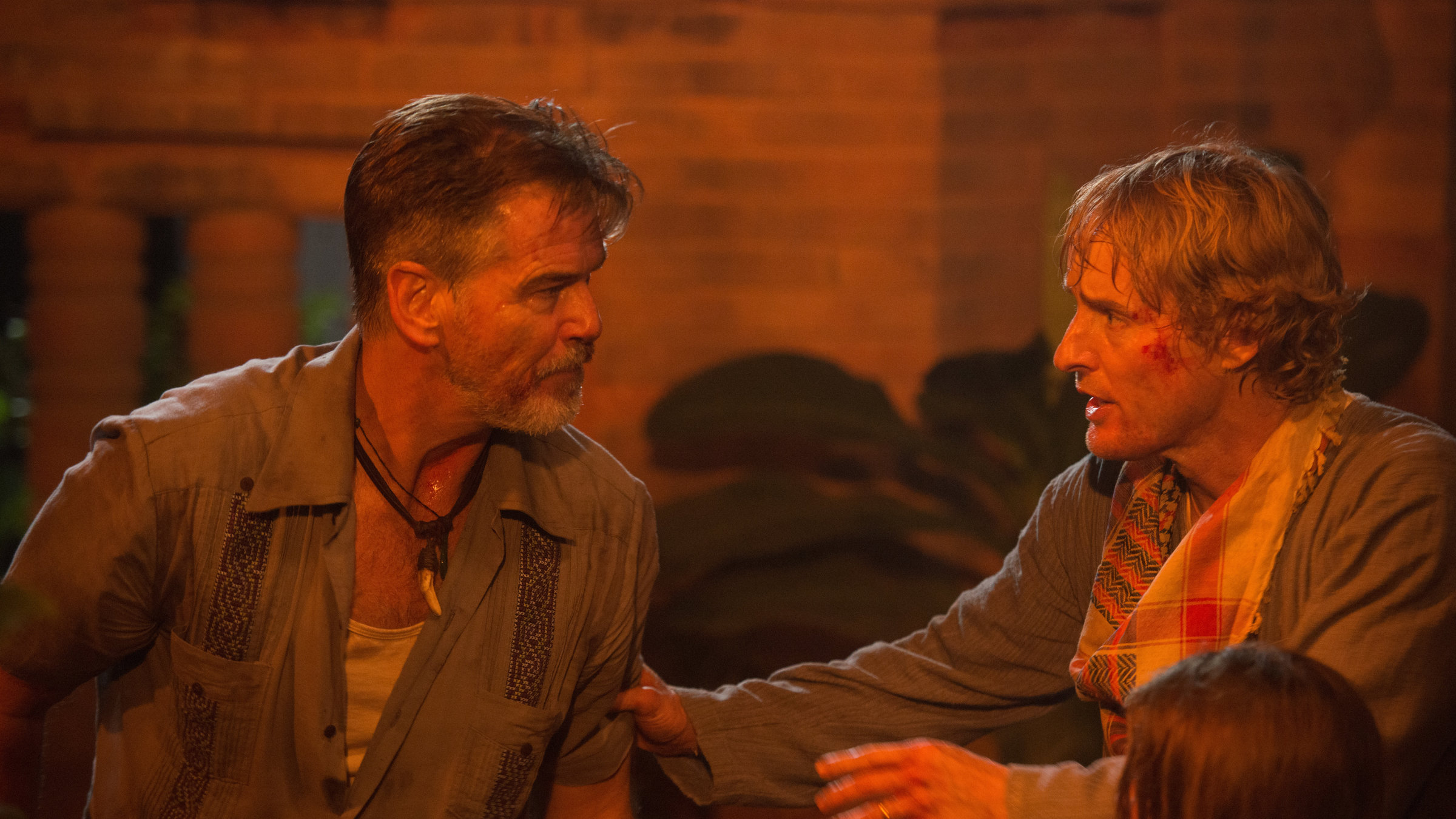 "No Escape - Renn um Dein Leben": Hammond (Pierce Brosnan) und Jack Dwyer (Owen Wilson) stehen sich gegenüber. Jack packt Hammond verzweifelt am Arm.