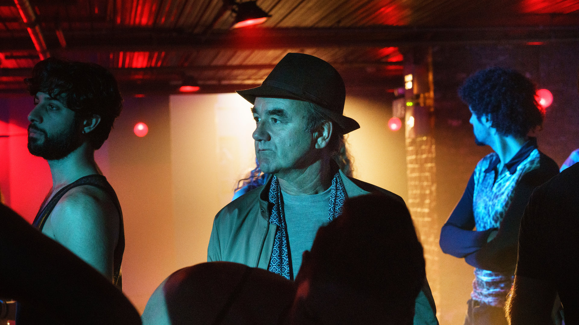 "Killing Eve - Ich kenn' sie doch": Bill Pargrave (David Haig) steht in einem dunklen Nachtclub inmitten einer Menschenmenge und schaut skeptisch zur Seite.