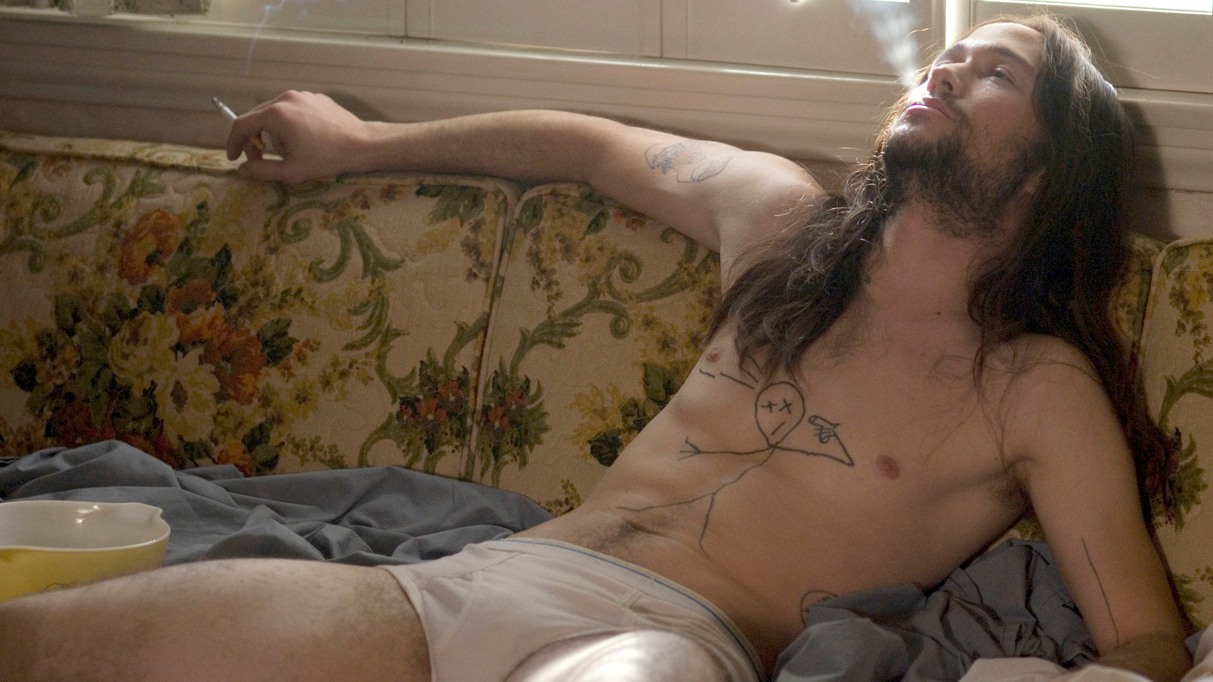 "Hesher - Der Rebell": Hesher (Joseph Gordon-Levitt) liegt entspannt mit nur einer Unterhose an, eine Zigarette rauchend, auf einer Couch.