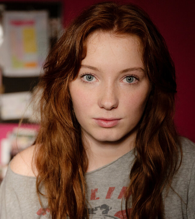 "So Damn Easy Going": Großaufnahme: Joanna (Nikki Hanseblad) steht in einem Zimmer vor einer roten Wand.