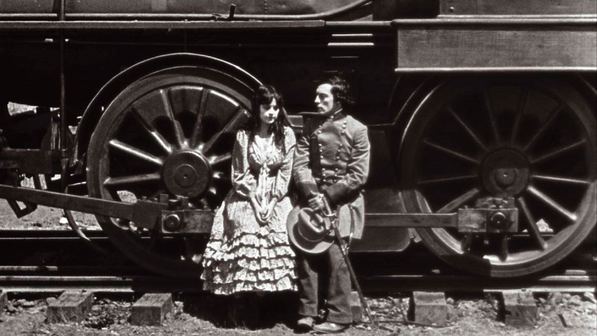 "Der General": Vor einer enorm großen Dampflokomotive sitzen ein Mann (Buster Keaton) in Soldatenuniform und eine junge Frau im Kleid.