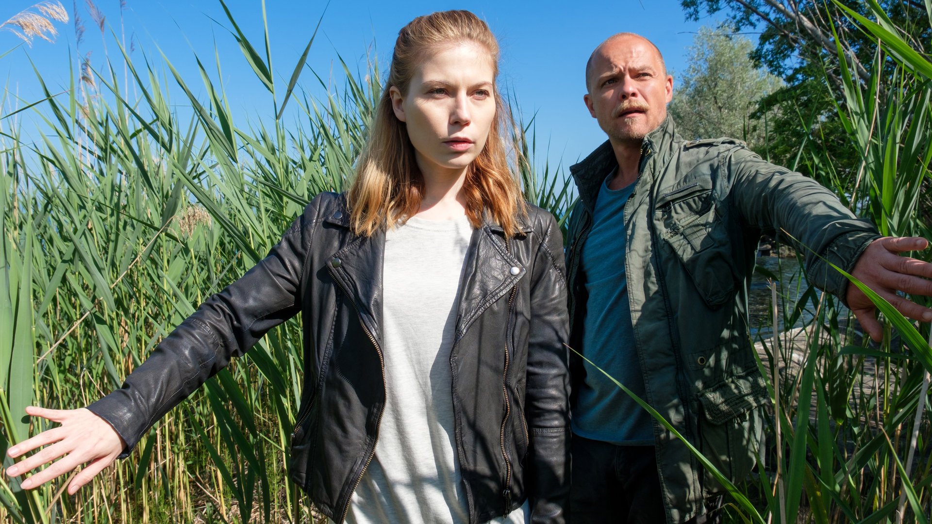 „Die Toten vom Bodensee - Die Meerjungfrau“: Zeiler (Nora Waldsätten) und Oberländer (Matthias Koeberlin) schieben Schilf zur Seite und sehen angespannt nach vorne.
