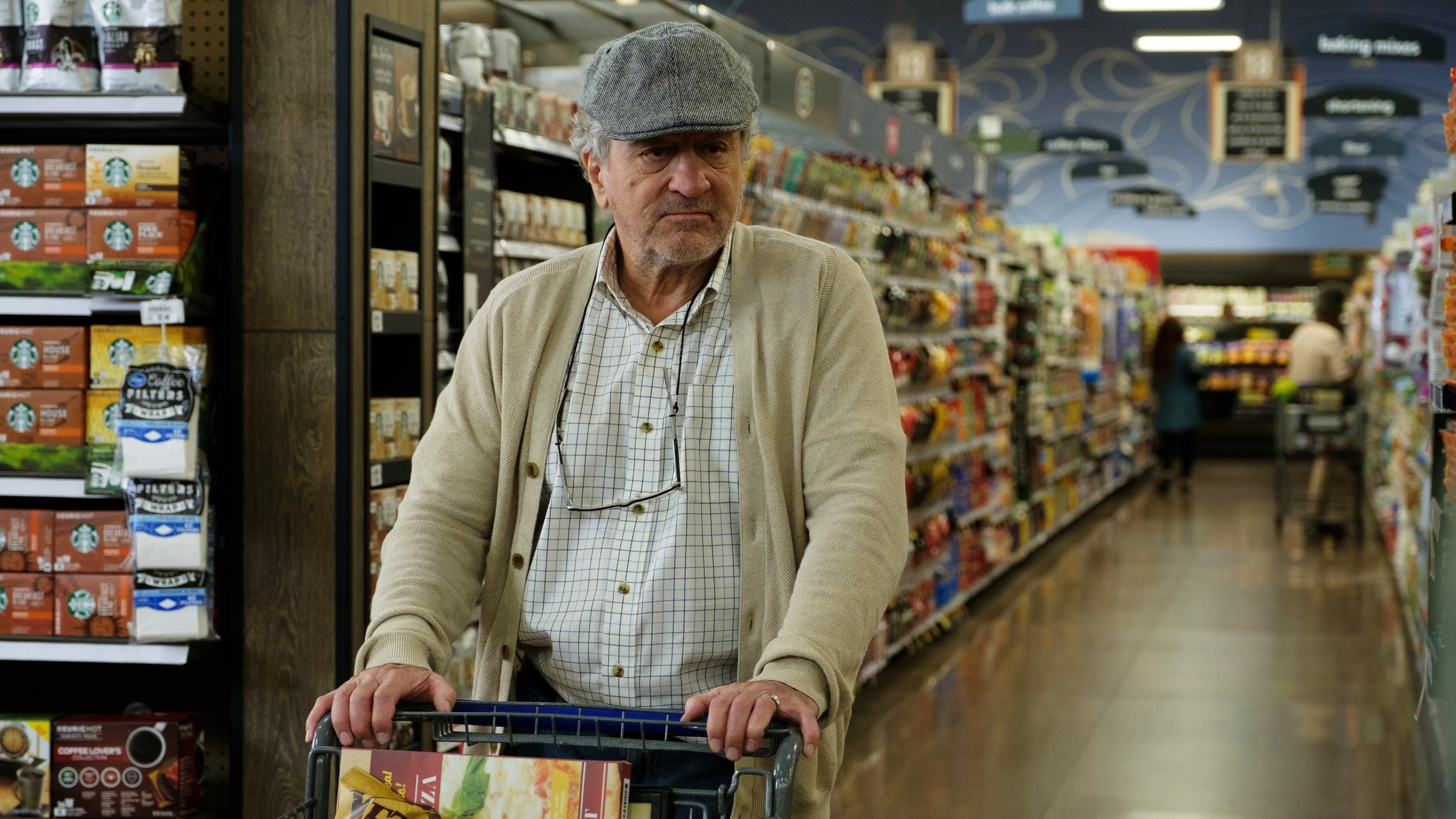 "Immer Ärger mit Grandpa": Ein mürrisch blickender älterer Herr, Ed (Robert De Niro), in Strickjacke und Baseball-Cap, schiebt in einem Supermarkt einen befüllten Einkaufswagen vor sich her.