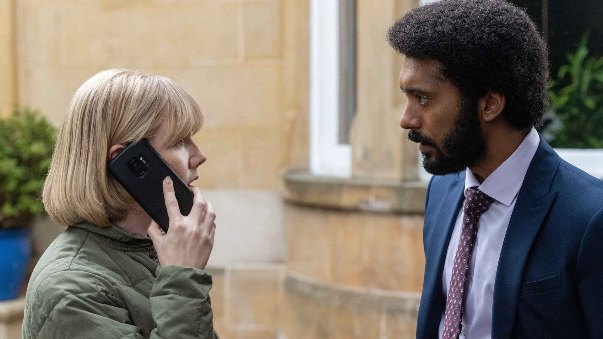 "Karen Pirie - Echo einer Mordnacht - Späte Sühne": Karen (Lauren Lyle) steht telefonierend vor dem Haus und schaut Phil (Zach Wyatt) an, der vor ihr steht.