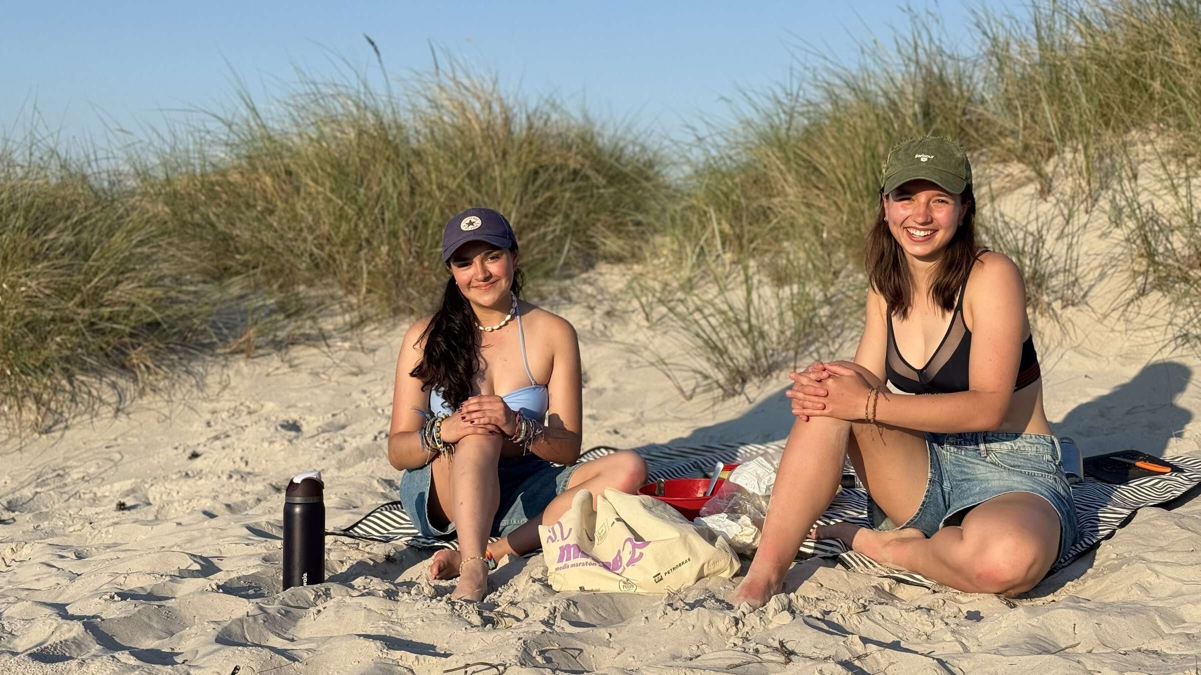 "ZDF.reportage: Urlaub auf dem Darß - Traumstrand der Ostsee": Zwei junge Frauen sitzen beim Picknick in den Dünen und schauen lächelnd in die Kamera.