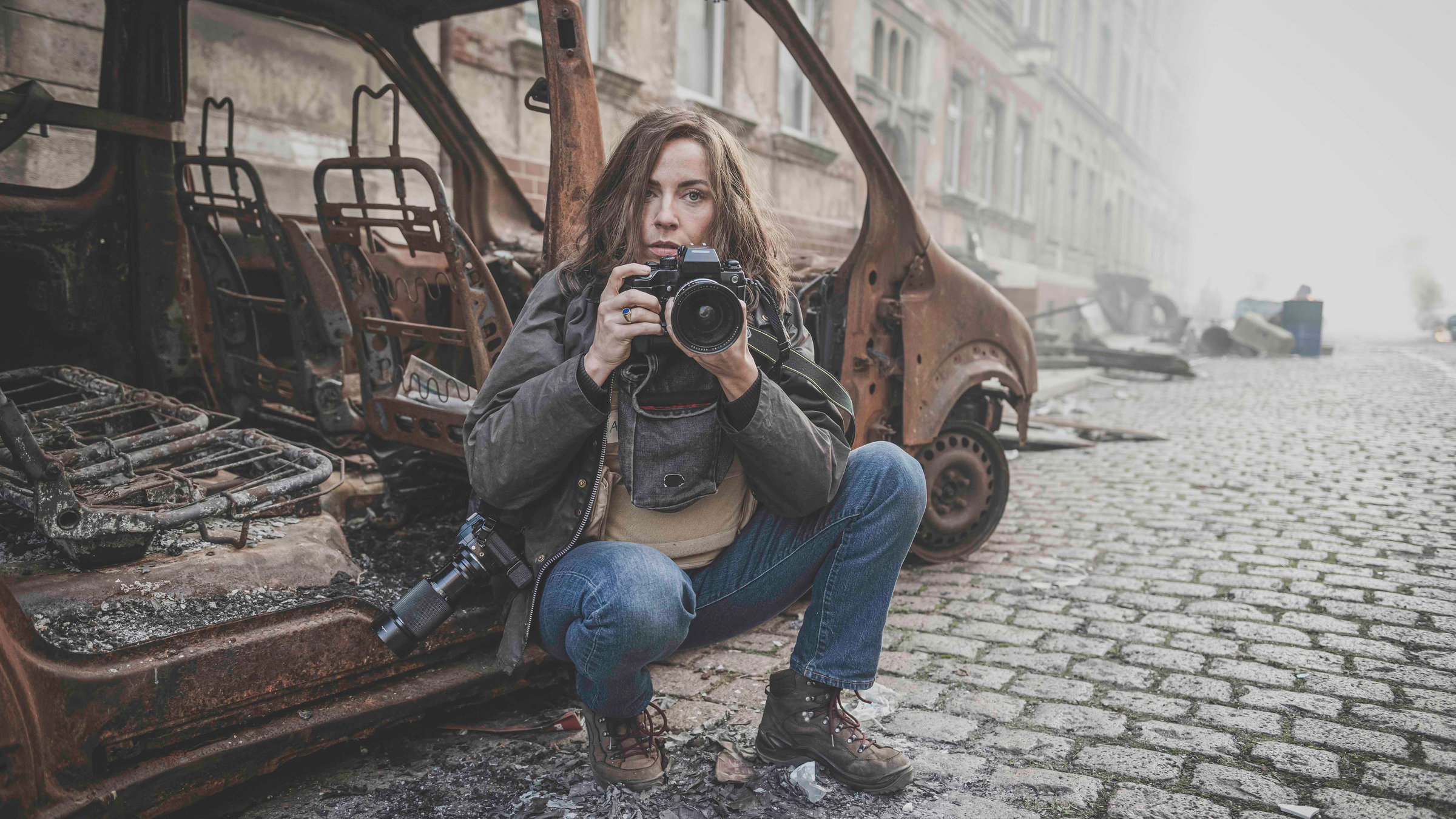"Die Bilderkriegerin": Anja Niedringhaus (Antje Traue) sitzt vor einem ausgebranntem Auto.
