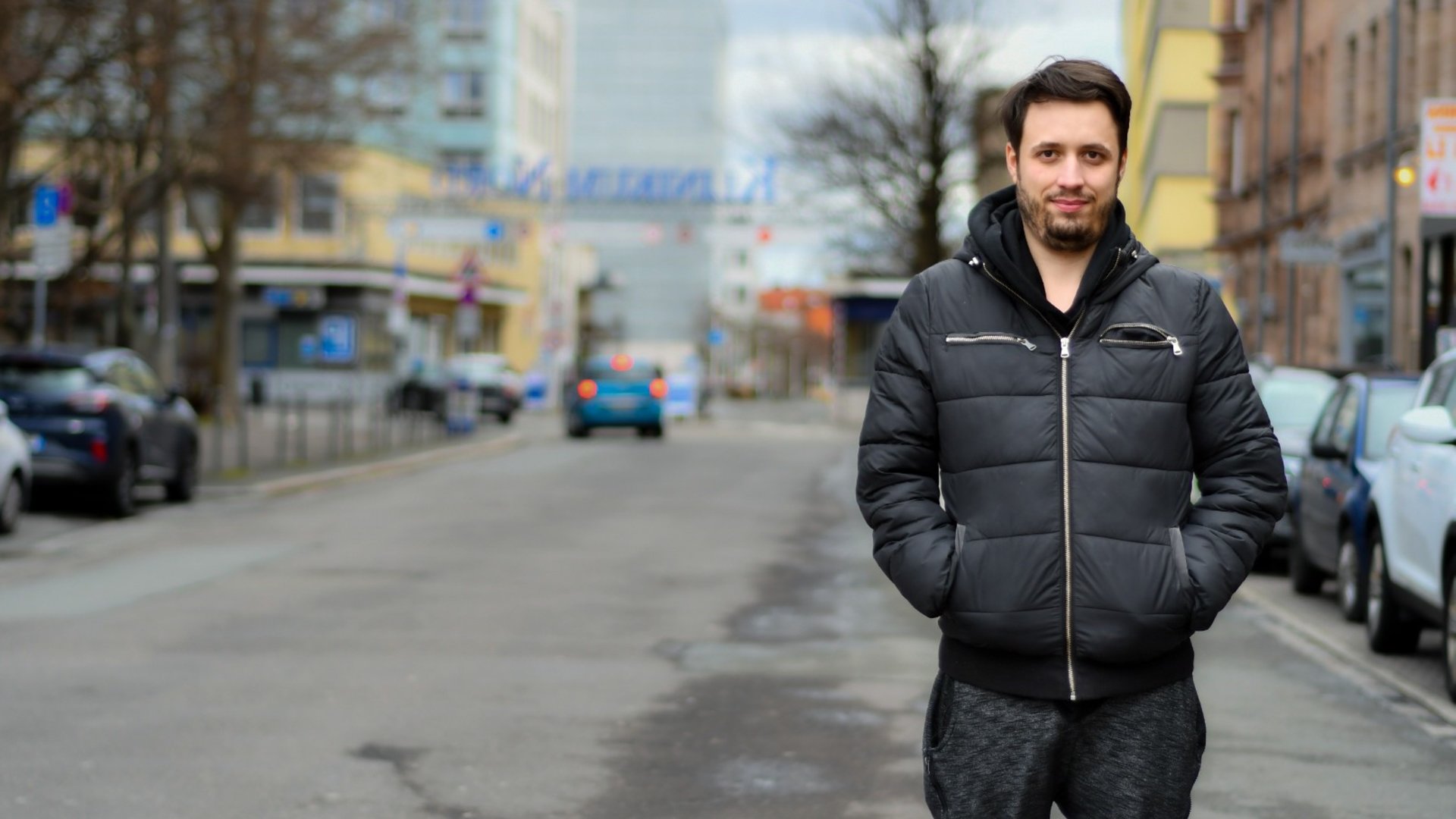 "einfach Mensch – Mario: Meine unsichtbare Not!": Mario steht auf einer Straße und lächelt in die Kamera.