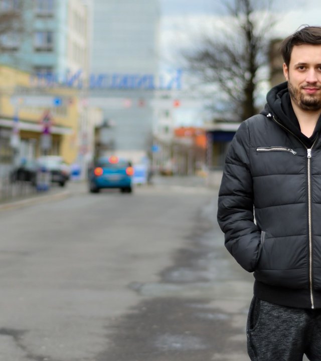 "einfach Mensch – Mario: Meine unsichtbare Not!": Mario steht auf einer Straße und lächelt in die Kamera.