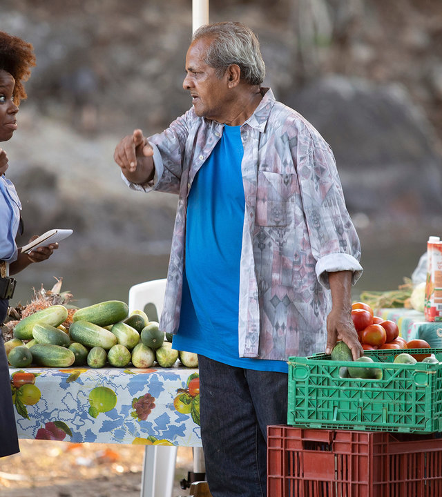 "Death in Paradise – Familienangelegenheiten": Officer Ruby Patterson (Shyko Amos) spricht mit einem Obstverkäufer, der ihr gegenüber steht.