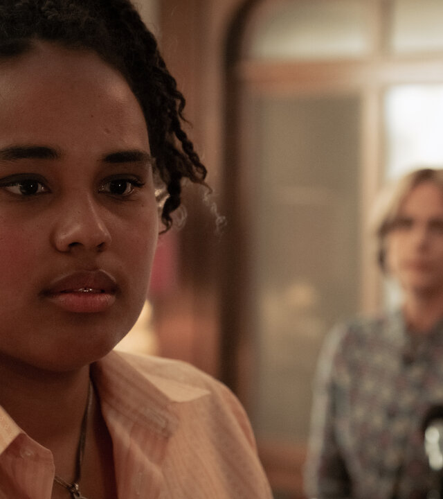 "Ku'damm 77": Linda Müller (Massiamy Diaby) steht in einem Raum und macht ein betrübtes Gesicht. Sie dreht Caterina Schöllack (Claudia Michelsen) den Rücken zu. Caterina sitzt hinter ihr auf einem Stuhl.