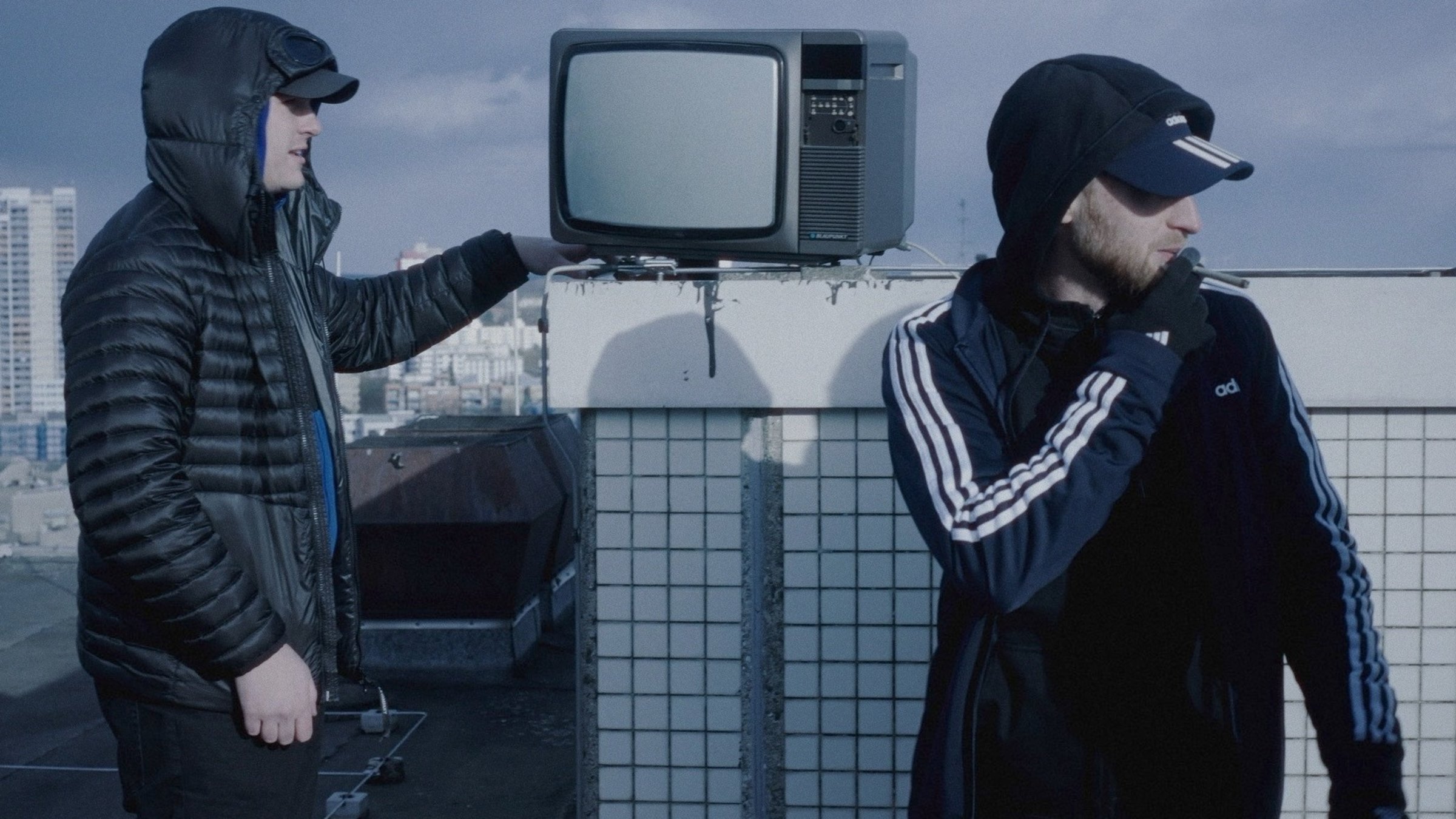 "Ab 18! - Luvres Release": Zwei junge Männer im Profil auf einem Hochhausdach, im Hintergrund steht ein alter Fernseher.