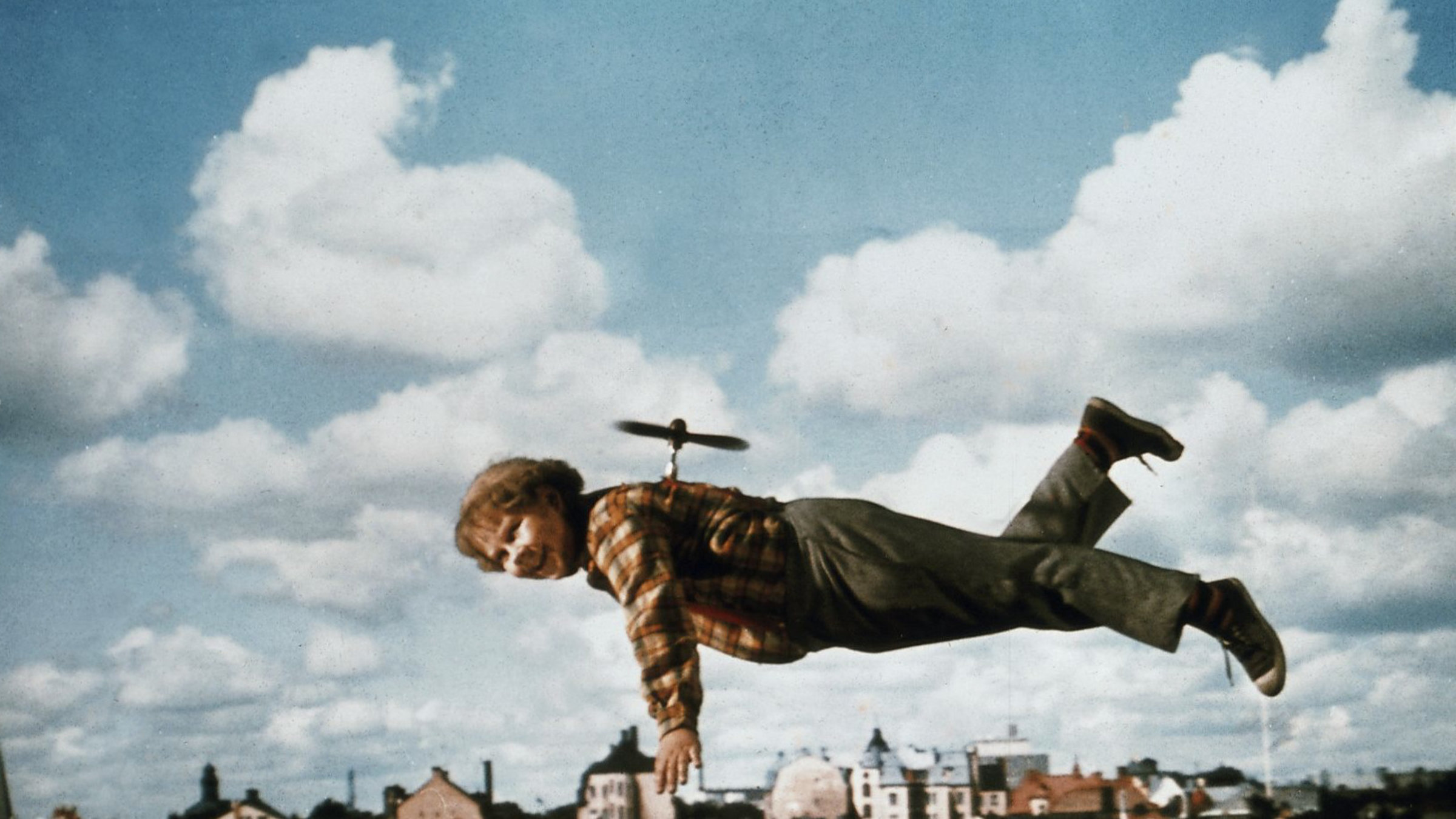 "Karlsson auf dem Dach": Karlson (Mats Wikström) fliegt mit einem Propeller auf dem Rücken über die Stadt.