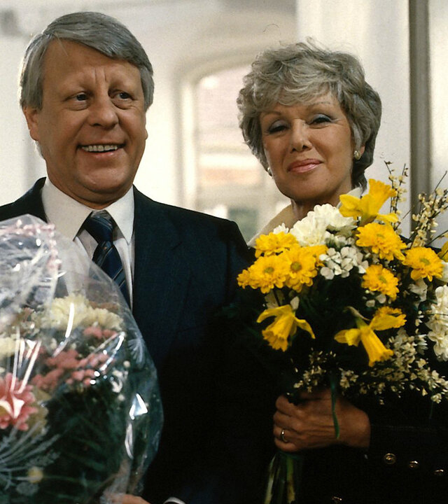 "Die Wicherts von nebenan: Silberhochzeit": Hannelore (Maria Sebaldt) und Eberhard (Stefan Orlac) stehen mit Blumensträußen in der Hand nebeneinander und lächeln.