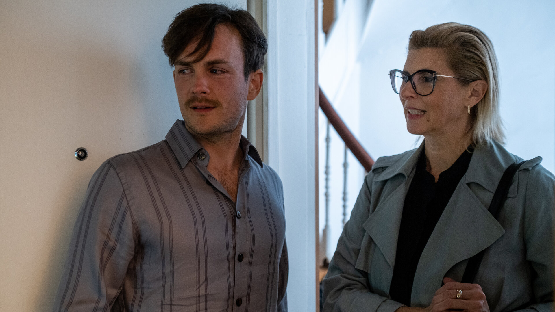 "SOKO Hamburg - Tödlicher Hass": Swantje Neumann (Paula Paul) steht im Türrahmen einer Wohnung neben Marco Althaus (Eric Klotzsch) und blickt lächelnd nach vorne. Marco Althaus steht seitlich von ihr und lehnt an der geöffneten Tür. Er blickt ebenfalls leicht lächelnd in die gleiche Richtung.