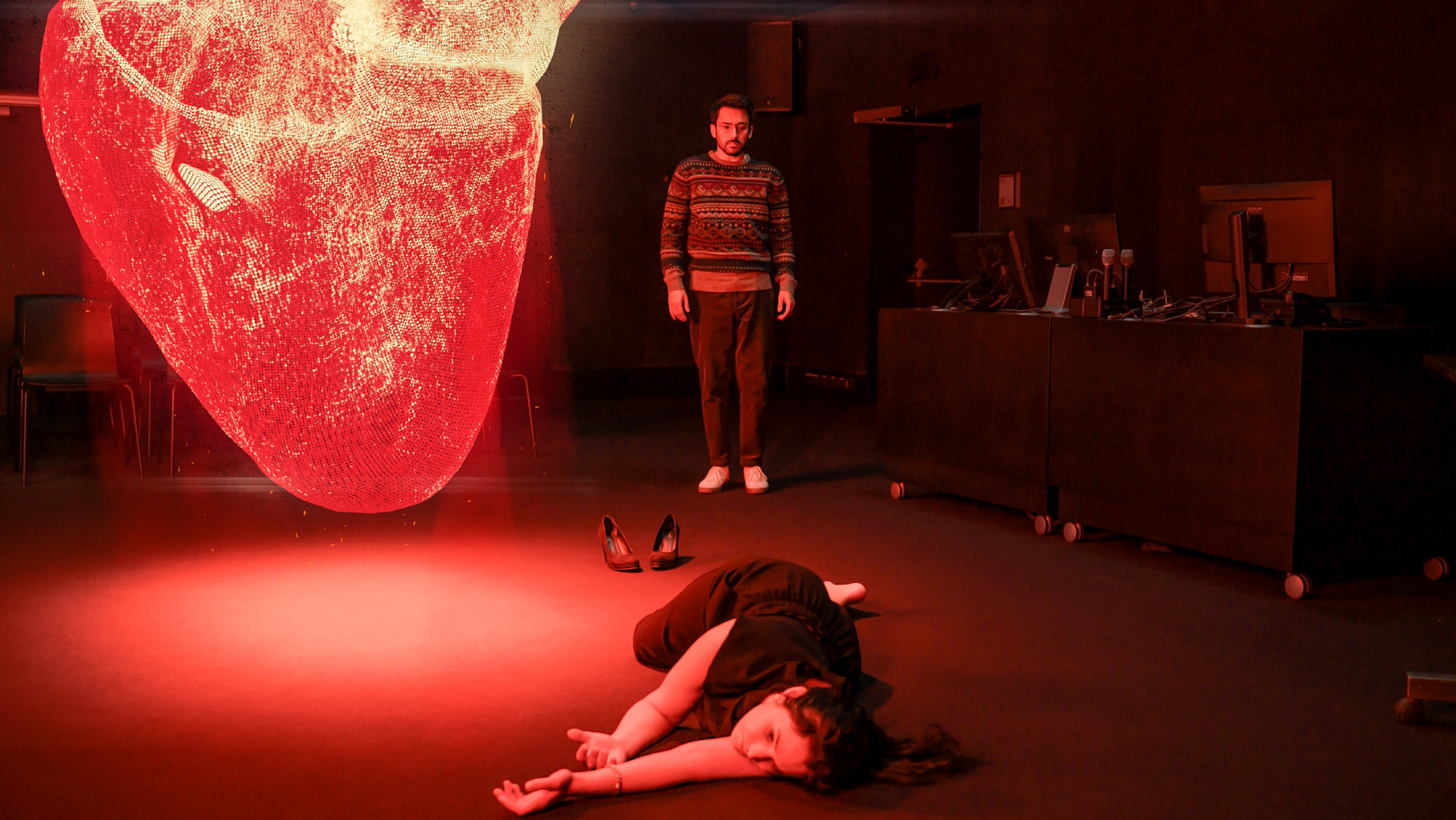 "SOKO Linz- Herzensbrecher": Ein dunkler Lehrraum wird von einem riesigen Hologrammherz rot erleuchtet. Milan Louka (Harwin Krawitz) starrt entsetzt auf den Boden vor sich, auf dem das Opfer liegt.