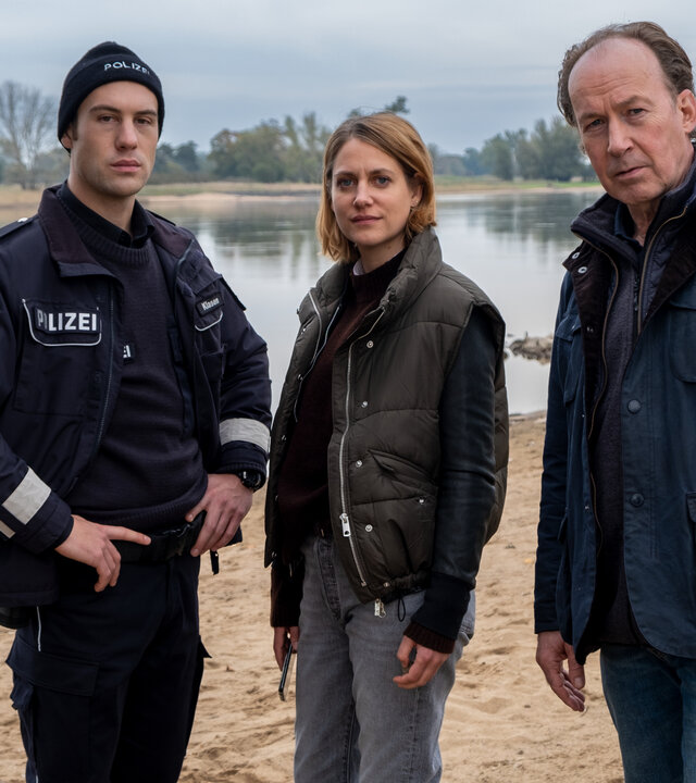 "Wendland - Stiller und das große Schweigen": Oliver Klasen (Malte Thomsen), Kira Engelmann (Bettina Burchard) und Jakob Stiller (Ulrich Noethen) stehen zusammen am Ufer.
