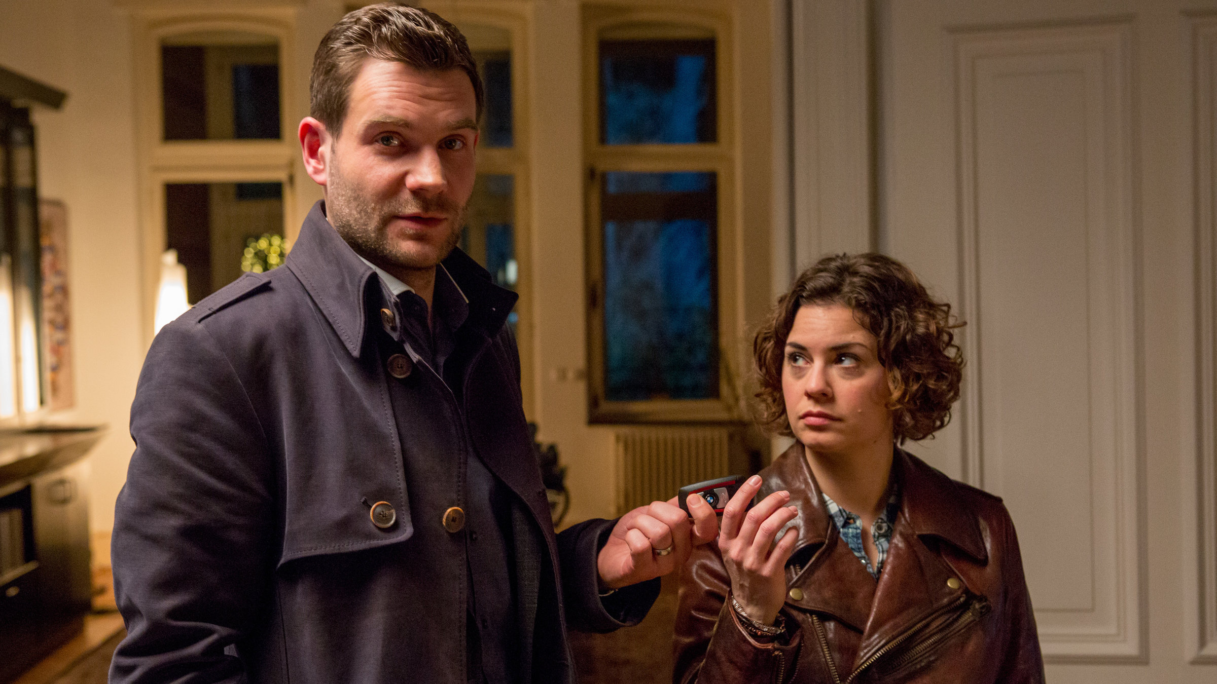 "SOKO Köln – Von fremder Hand": Die Kommissare Jonas Fischer (Lukas Piloty) und Lilly Funke (Tatjana Kästel) stehen nebeneinander in einer Altbauwohnung. Jonas überreicht Lilly etwas, sie sieht ihn an.