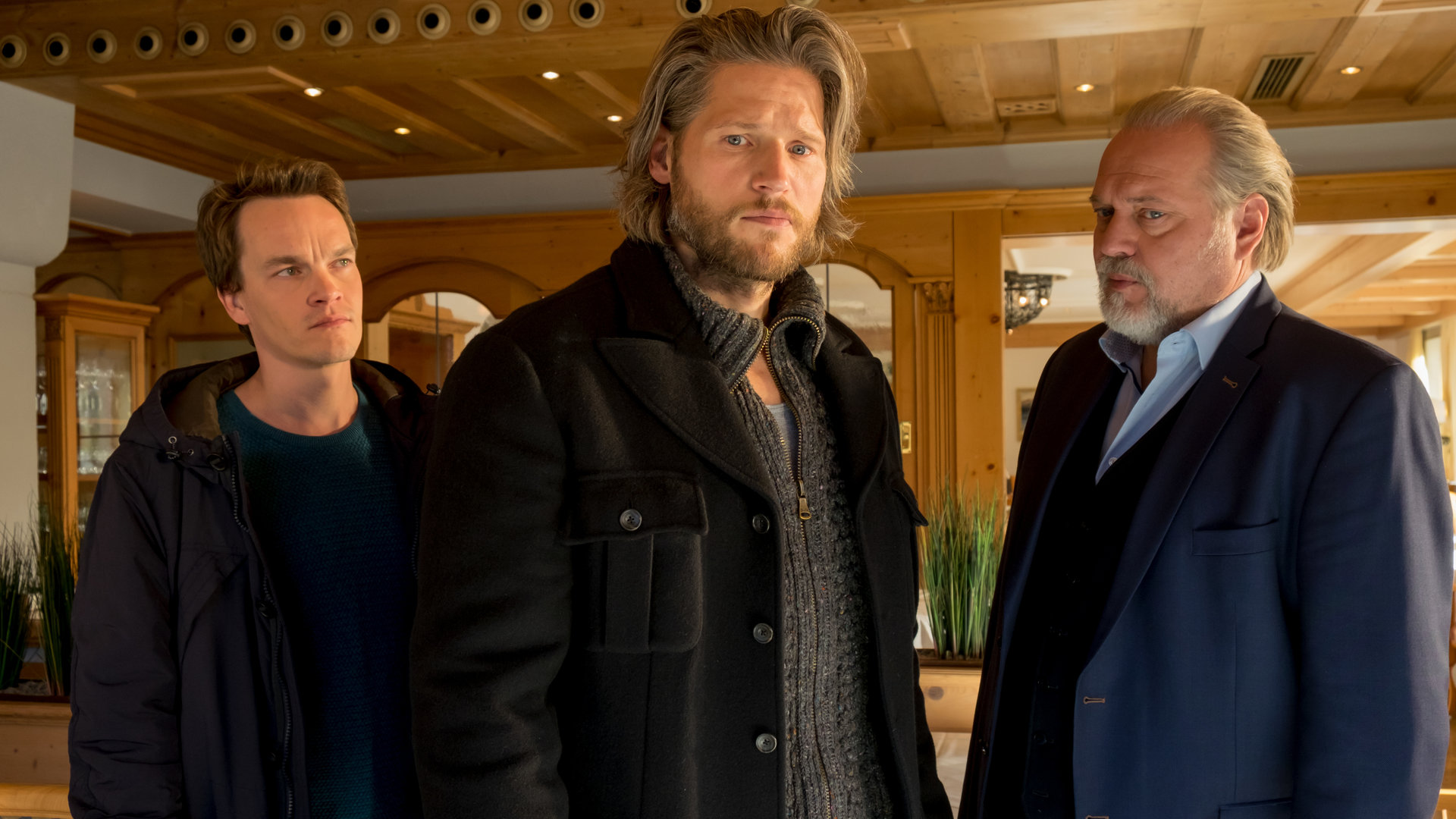 "Der Alte - Gerechtigkeit": Tom Kupfer (Ludwig Blochberger) und Richard Voss (Jan-Gregor Kremp) stehen mit Stefan Dombach (Sebastian Ströbel) in der Hotellobby. Dombach hat den Kommissaren den Rücken zugewandt, die ihm kritische Blicke zuwerfen.