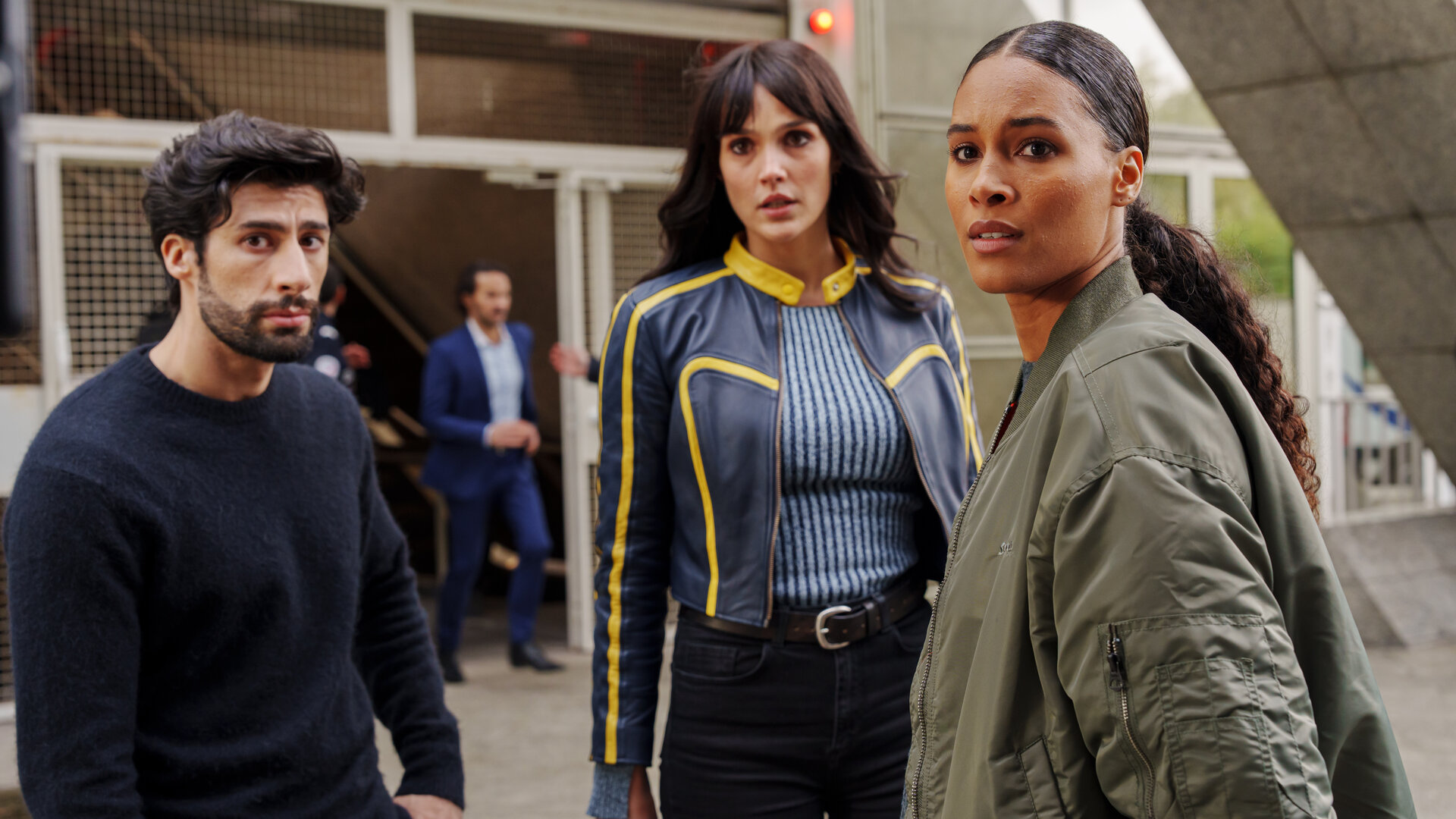 "Cat's Eyes - Gwen": Quentin (MB14), Tamara (Camille Lou) und Gwen (Cindy Bruna) stehen im Freien vor einem Gebäude. Im Hintergrund ist unscharf ein weiterer Mann zu sehen.
