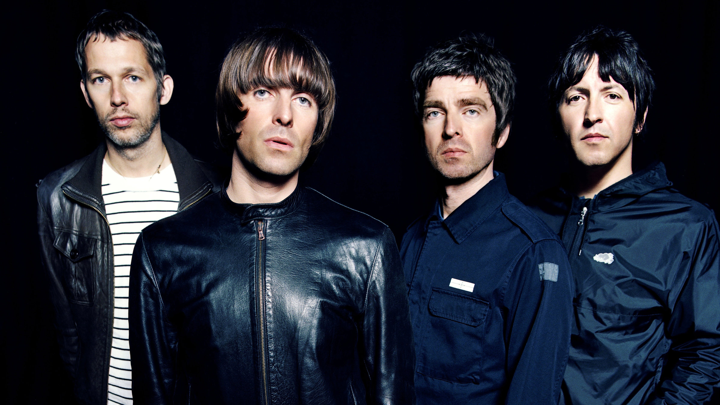"Oasis: Live at Barrowlands": Die Mitglieder der Band Oasis stehen nebeneinander vor einer schwarzen Wand und blicken in die Kamera. Alle vier sind mit schwarzen oder dunkelblauen Jacken bekleidet.