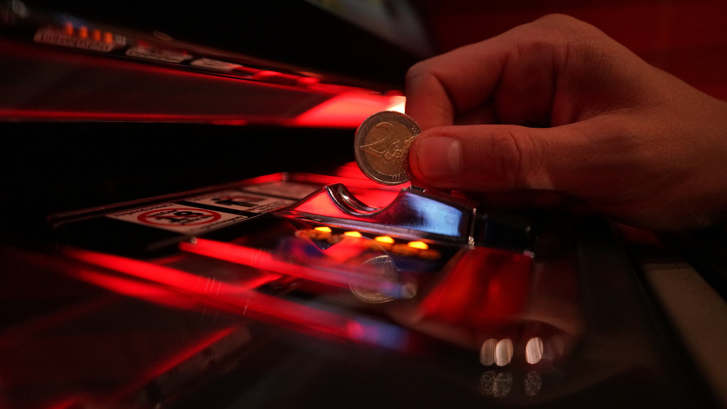 "ZDF.reportage: Vorsicht Glücksspiel! - Zocken bis zur Pleite": Eine Hand wirft eine Münze in einen Spielautomaten.