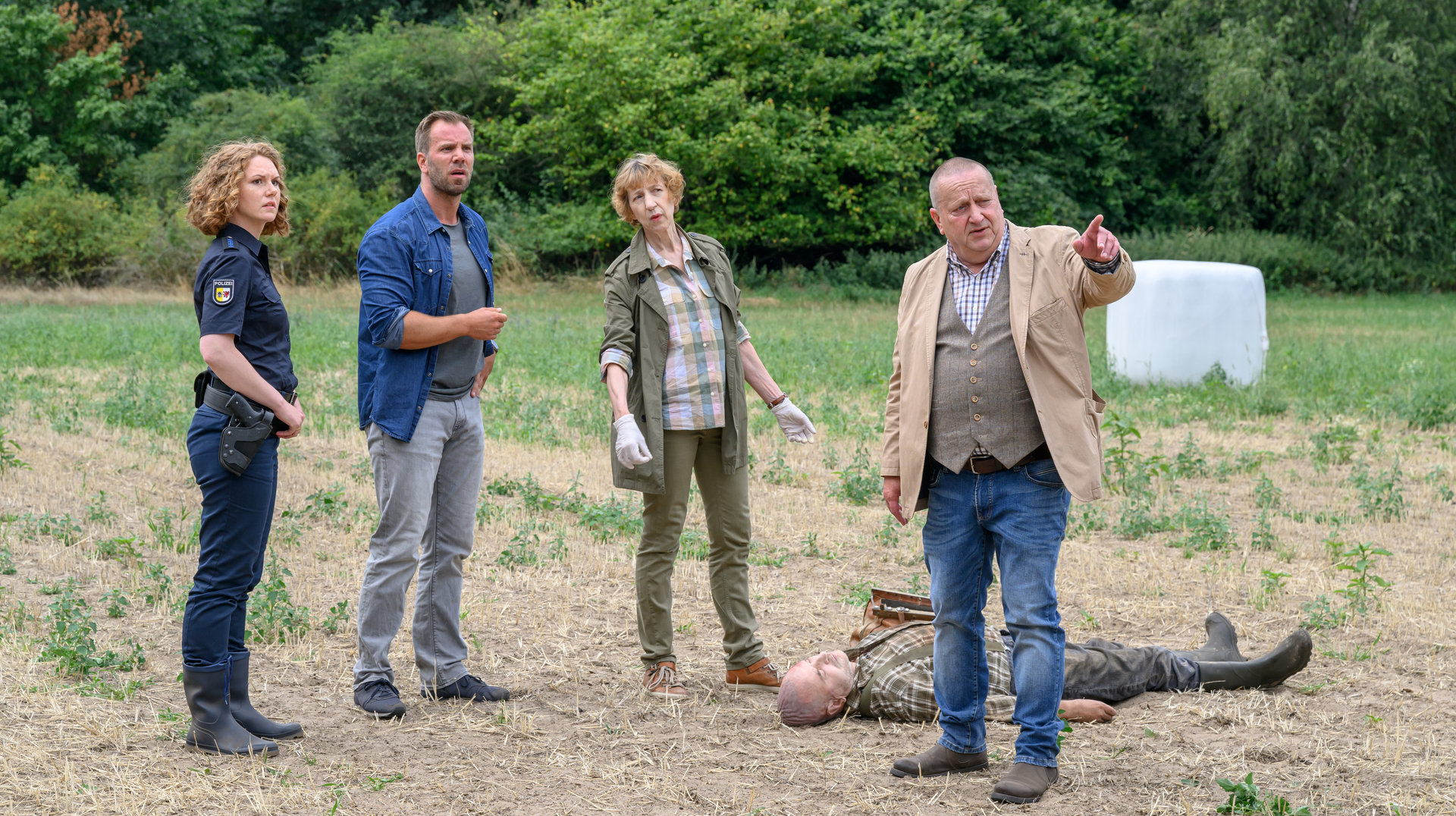 "SOKO Wismar – Bauernsterben": Die Ermittelnden Paula Moorkamp (Stella Hinrichs), Lars Pöhlmann (Dominic Boeer), Dr. Helene Sturbeck (Katharina Blaschke) und Jan-Hinrich Reuter (Udo Kroschwald) stehen auf einem Acker um die Leiche von Thiess Passow (Harald Krull) versammelt.