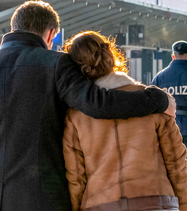 "SOKO Kitzbühel - Abschied": An einem Bahnsteig läuft Lukas (Jakob Seeböck) mit Nina (Julia Cencig) entlang. Er legt seinen Arm um ihre Schulter. Vor ihnen wird eine Frau von der Polizei begleitet. Alle Personen sind von hinten zu sehen.