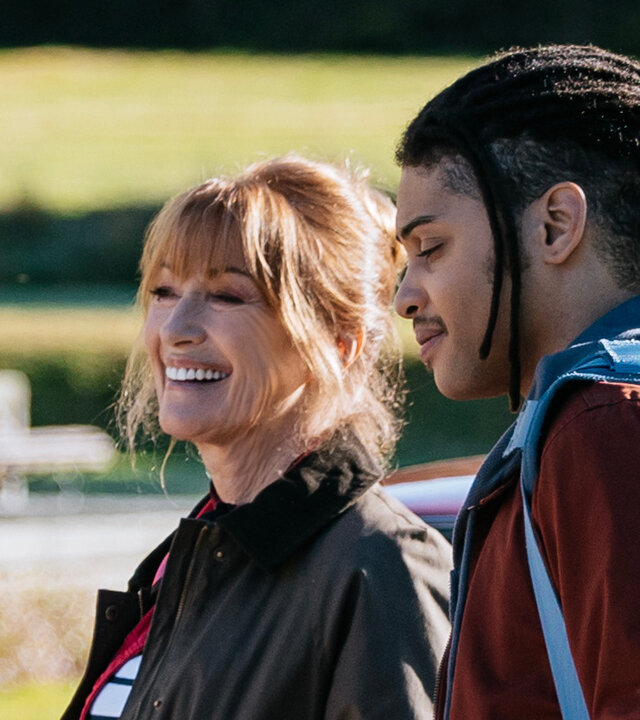 "Harry Wild – Mörderjagd in Dublin - Ein Hochzeits-Crasher aus der Hölle (1)": Harry Wild (Jane Seymour) und Fergus Reid (Rohan Nedd) stehen im Freien vor einem Auto. Bei wirken sehr gut gelaunt. Fergus trägt eine große Umhängetasche über der rechten Schulter.