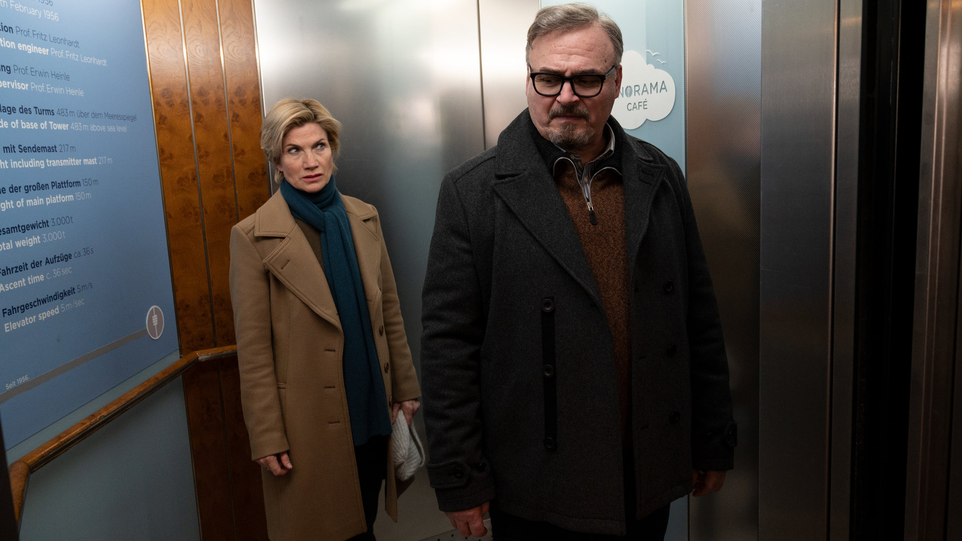 "SOKO Stuttgart – Tod im Turm": Martina Seiffert (Astrid M. Fünderich) und Aufzugsführer Jürgen Spengler (Oliver Breite) stehen im Aufzug des Stuttgarter Fernsehturms. Die Kriminalhauptkommissarin steht hinter dem Aufzugsführer und schaut ihn mit misstrauischem Blick an.