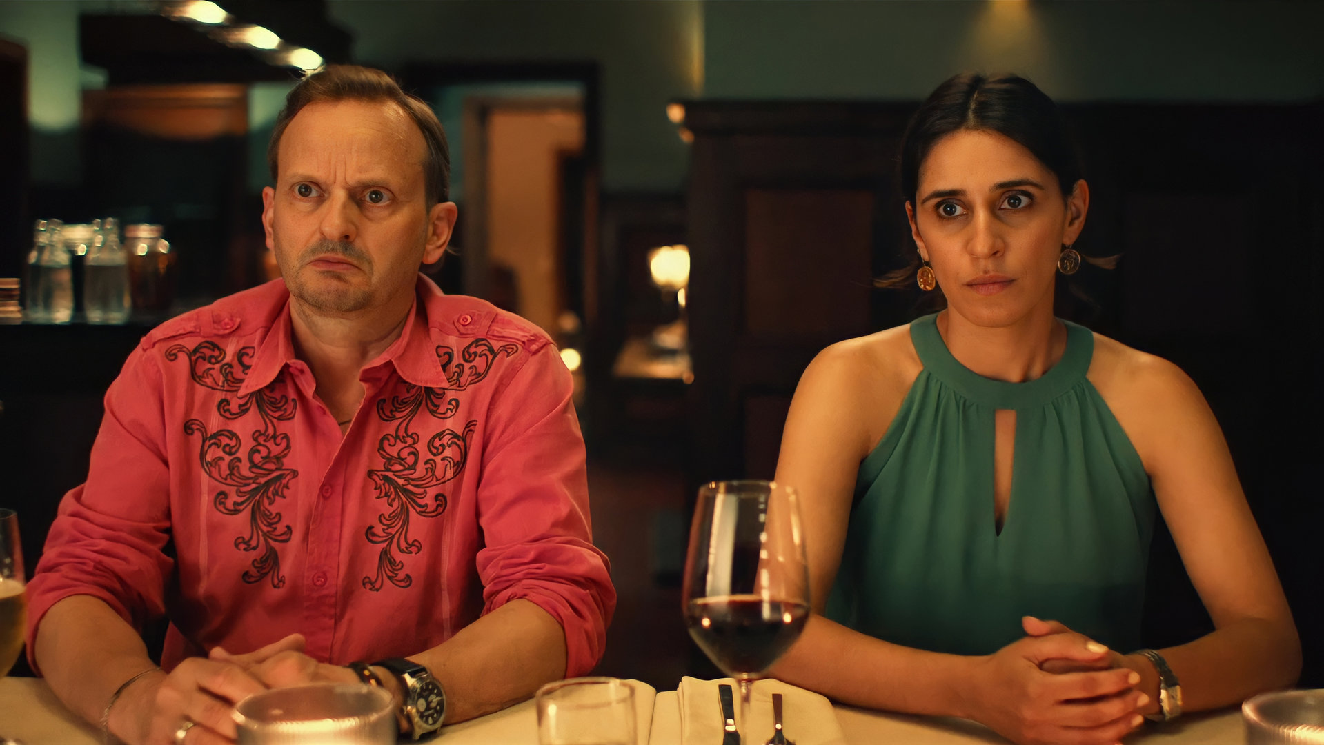 "Doppelhaushälfte - Amour fou": Mari (Maryam Zaree) und Andi (Milan Peschel) sitzen beide ungläubig blickend, mit verschränkten Händen, an einem festlich gedeckten Tisch.