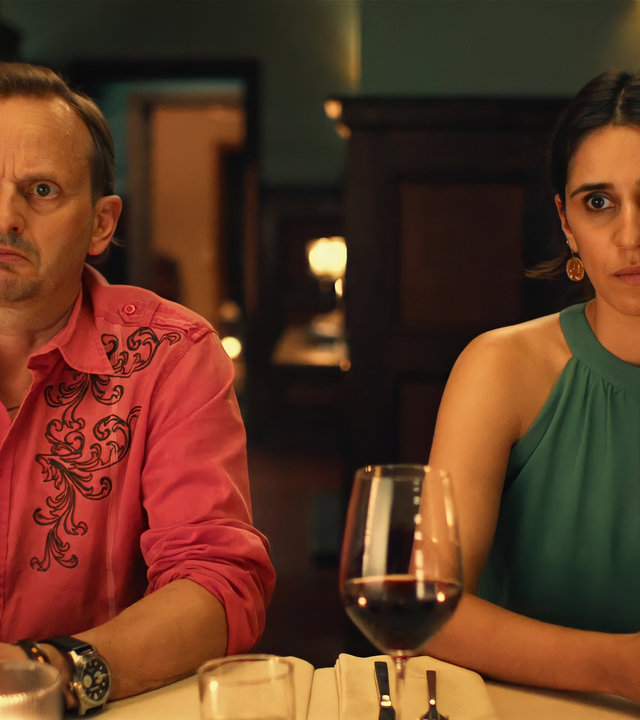"Doppelhaushälfte - Amour fou": Mari (Maryam Zaree) und Andi (Milan Peschel) sitzen beide ungläubig blickend, mit verschränkten Händen, an einem festlich gedeckten Tisch.