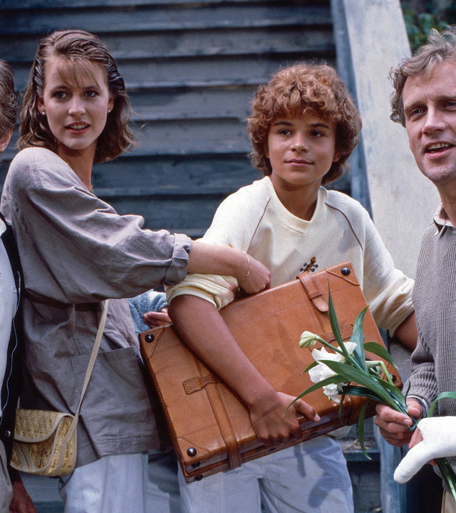 "Oliver Maass - Das Spiel mit der Zaubergeige": Oliver (Josef Gröbmayr), sein Vater (Robert Atzorn), Welter (Horst Kummeth) und Julia (Anja Schüte) stehen vor einem Treppenaufgang und schauen gelassen in die Ferne.
