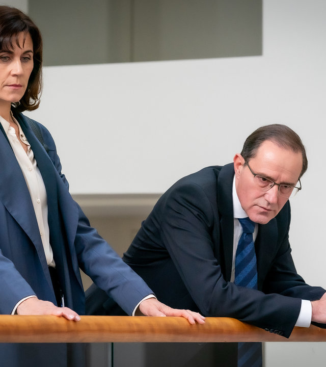 "Furia (2)": In einem großen Gebäude steht Kathi Falke (Nina Kunzendorf) an einer Brüstung neben Staatssekretär Böhringer (Stefan Kurt), der sich mit den Unterarmen auf den Handlauf stützt.