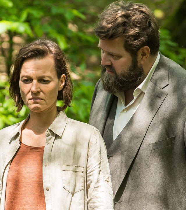 "Ein Fall für zwei - Der Mann aus dem Wald": Ella Warnke (Maria Simon) und Benjamin Hornberg (Antoine Monot) stehen in einem sonnendurchfluteten Wald. Die Umgebung ist dicht bewachsen, das Sonnenlicht fällt durch die Blätter und erzeugt helle Flecken auf ihrer Kleidung.