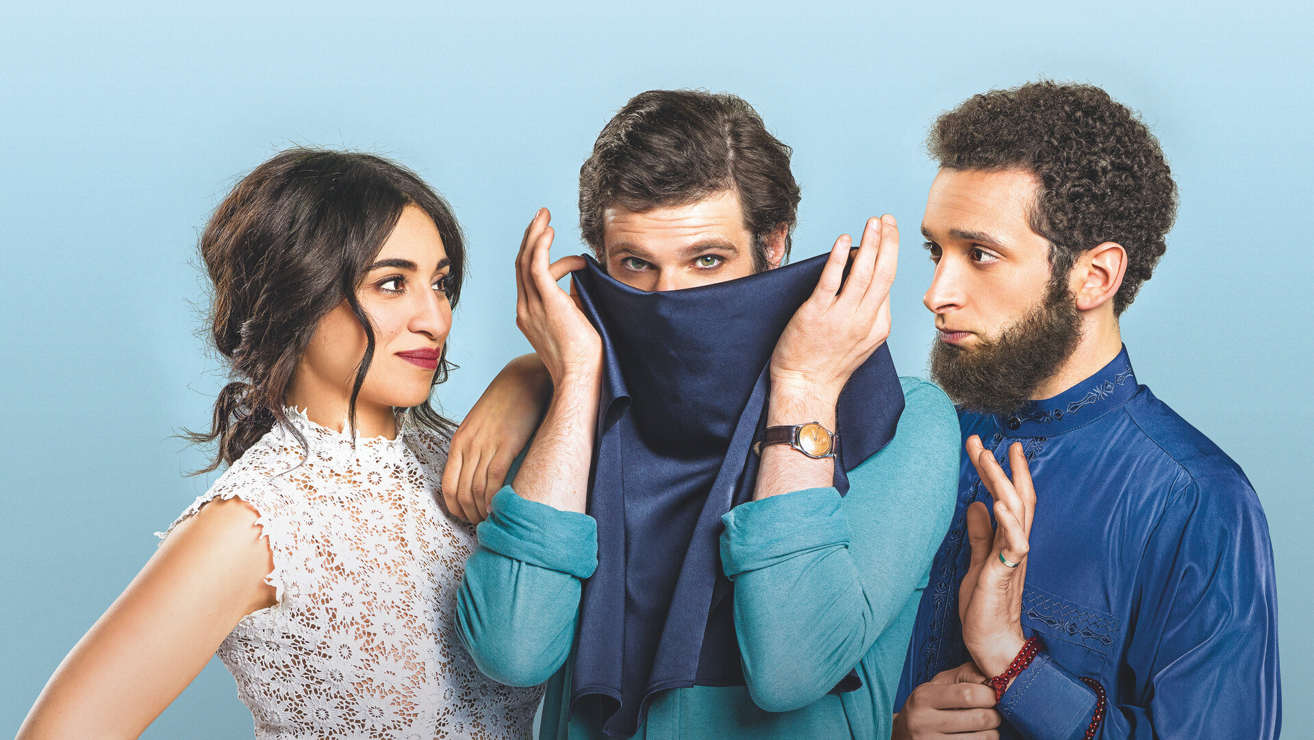 "Voll verschleiert": Leila (Cámelia Jordana), Armand (Félix Moati) und Mahmoud (William Lebghil) stehen nebeneinander vor einem hellblauen Hintergrund. Leila und Mahmoud, der ein dunkelblaues Gewand trägt, stehen links und rechts von Armand und blicken ihn an. Armand steht in der Mitte und hält sich einen dunkelblauen Niqab vor den Mund.