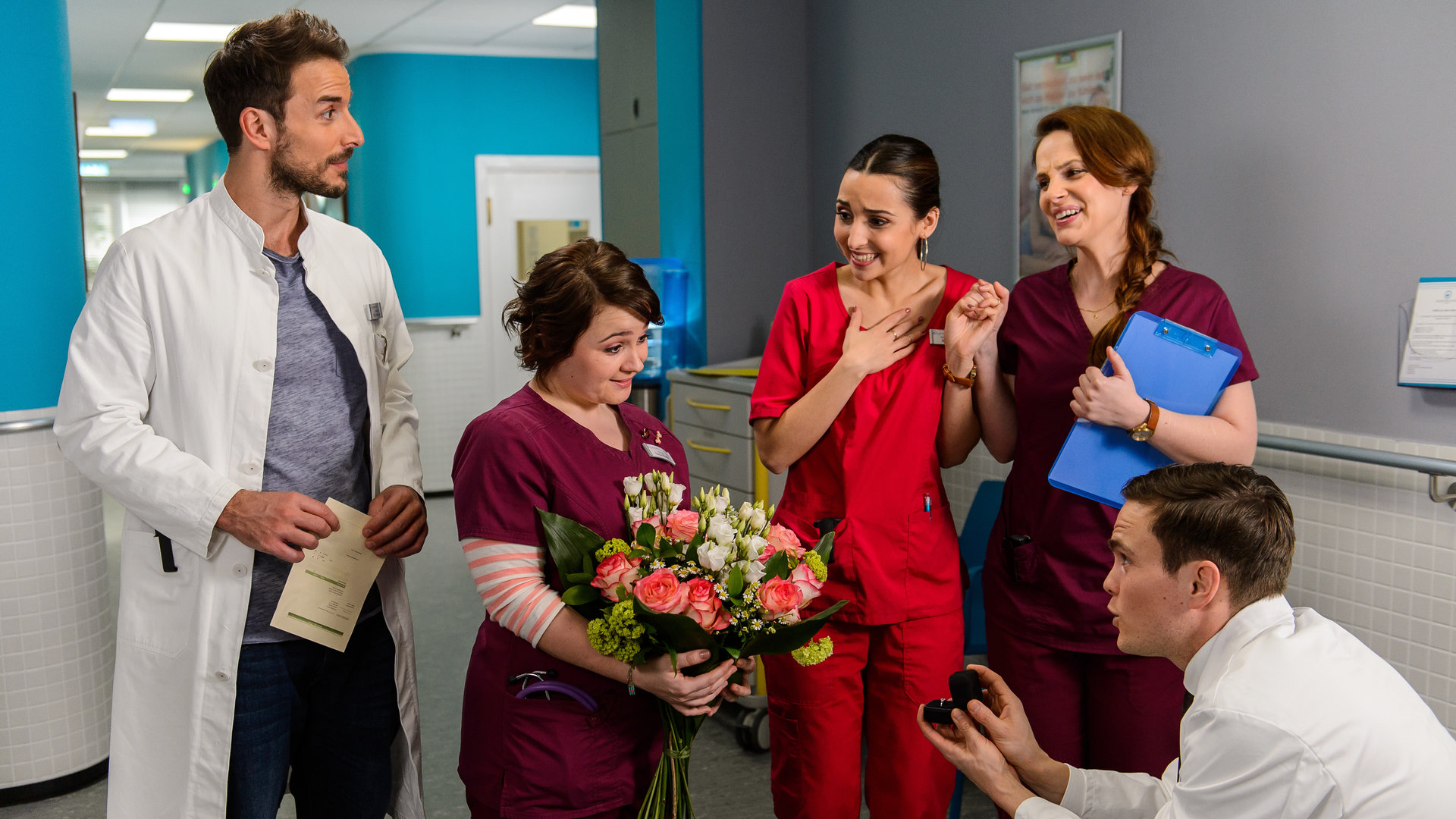 "Bettys Diagnose - Einer für den anderen": Dr. Tobias Lewandowski (Eric Klotzsch) macht Talula Pfeifer (Carolin Walter) vor den Augen der Kollegen Dr. Frank Stern (Max Alberti), Ava Edemir (Rona Özkan) und Hanna Winter (Marie Zielcke) einen Heiratsantrag.