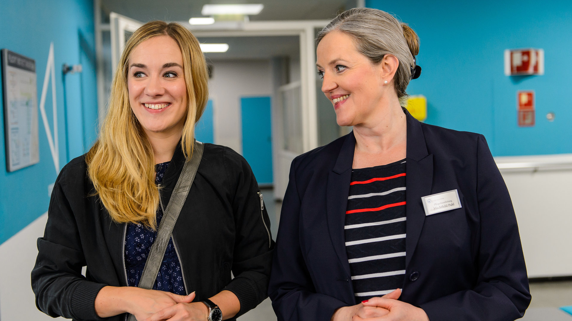 "Bettys Diagnose - Verlustängste": Betty Weiss (Annina Hellenthal) und Mechthild Puhl (Sybille J. Schedwill) unterhalten sich amüsiert im Krankenhausflur.