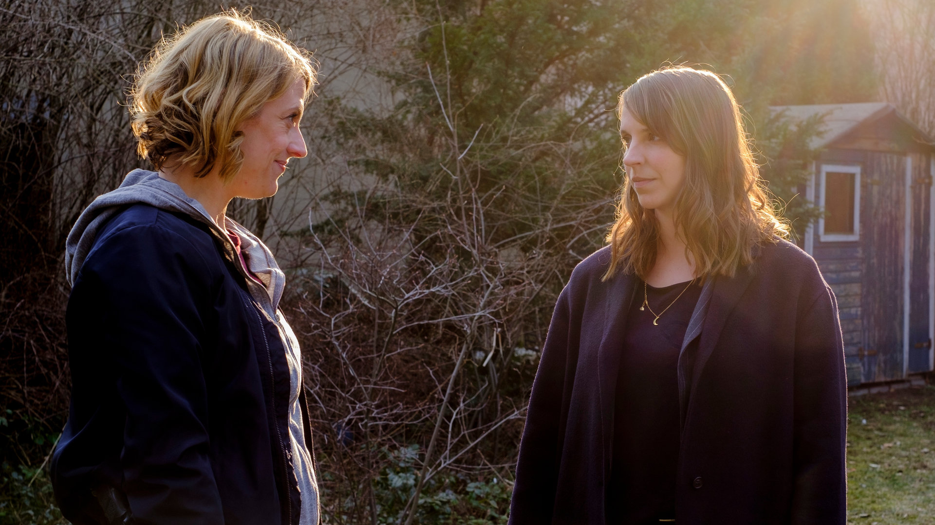 "SOKO Potsdam - Wenn es dunkel wird": Luna Kunath (Caroline Erikson) steht mit ihrer neuen Kollegin Tamara Meurer (Anja Pahl) in einem Garten. Im Hintergrund sind Büsche, Bäume und eine Gartenhütte zu sehen.