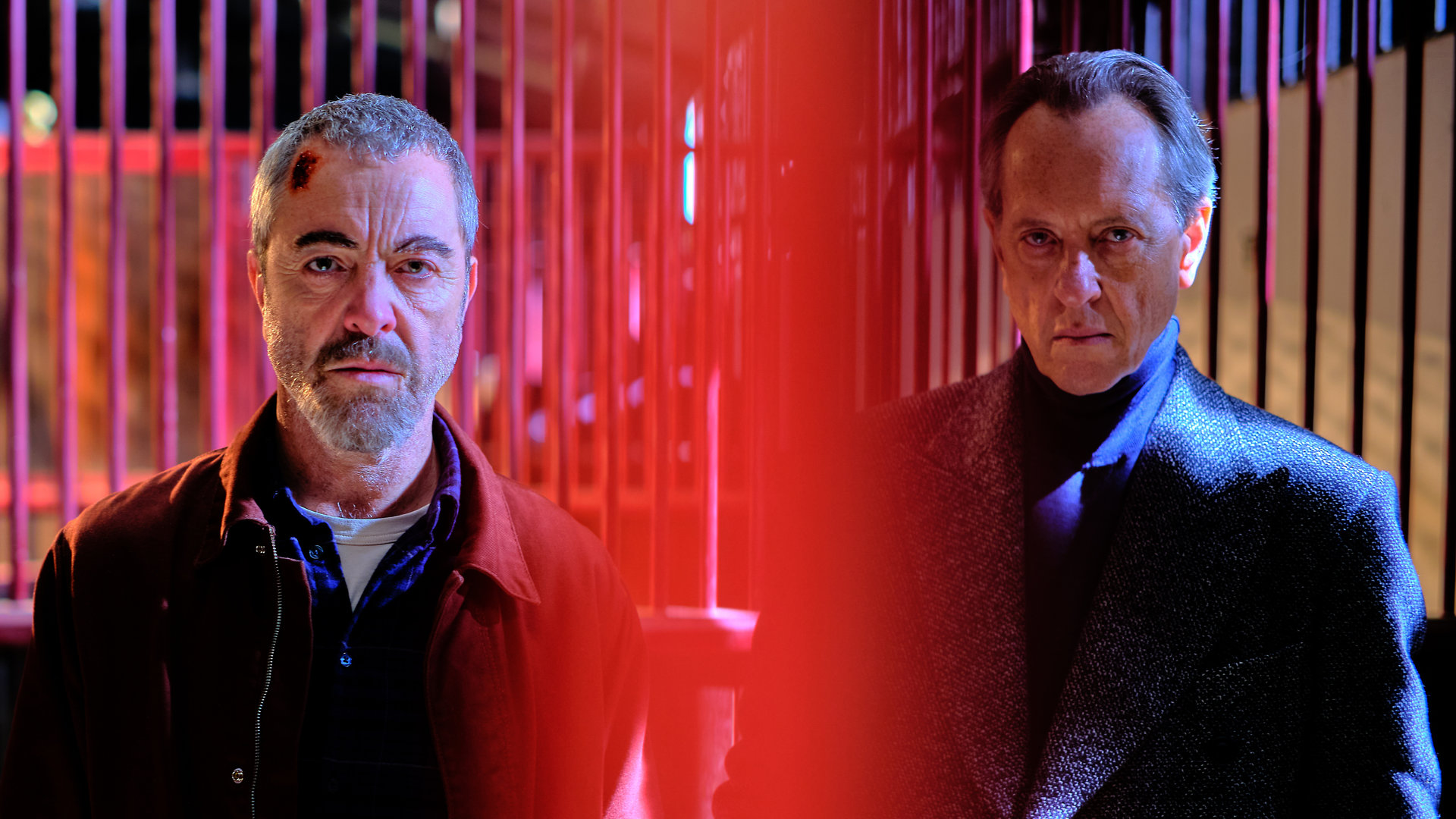 "Suspect - Folge 6: Harry": Danny (James Nesbitt) und Harry Carr (Richard E. Grant) stehen nebeneinander vor den Pferdeboxen auf der Rennbahn.