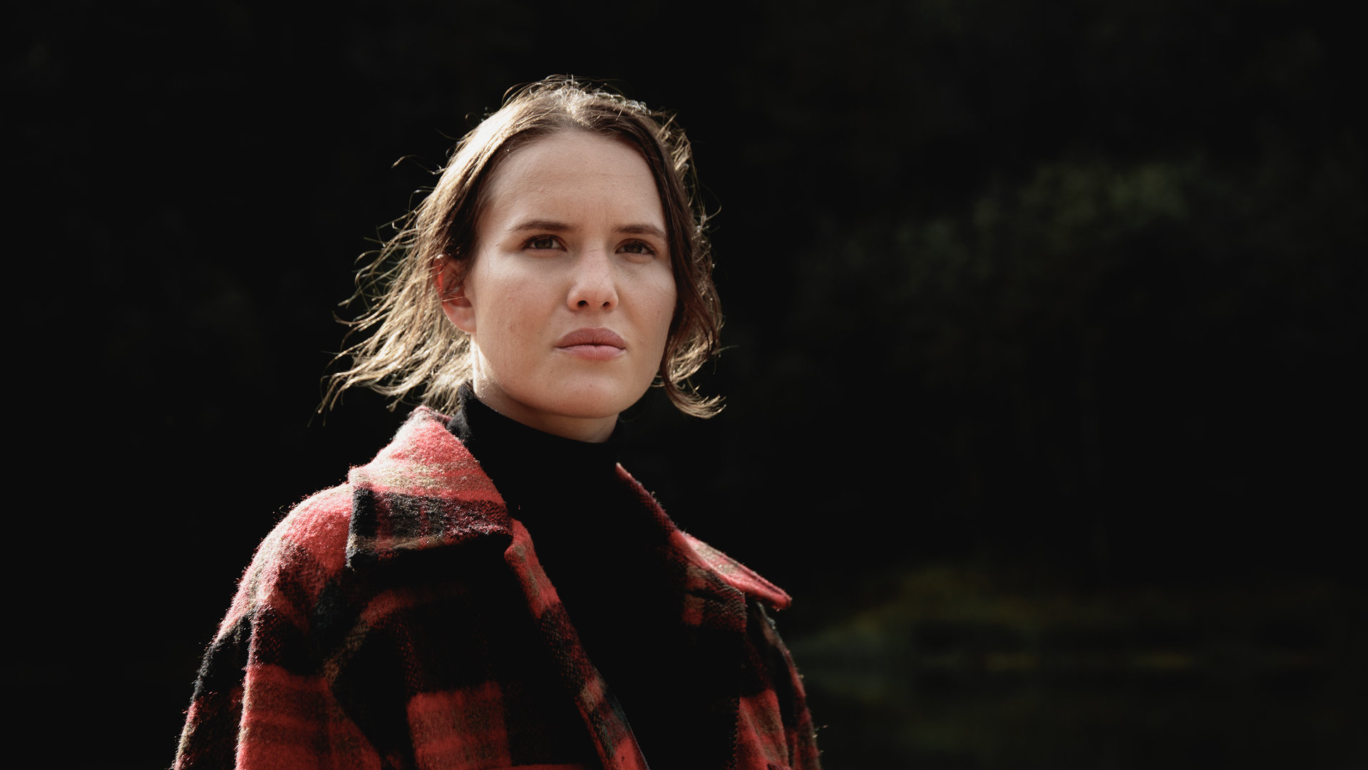 "Cryptid - Das Opfer von Lisa": Lisa (Astrid Morberg) steht mit ihrer Jacke draußen und schaut in Gedanken in die Ferne.