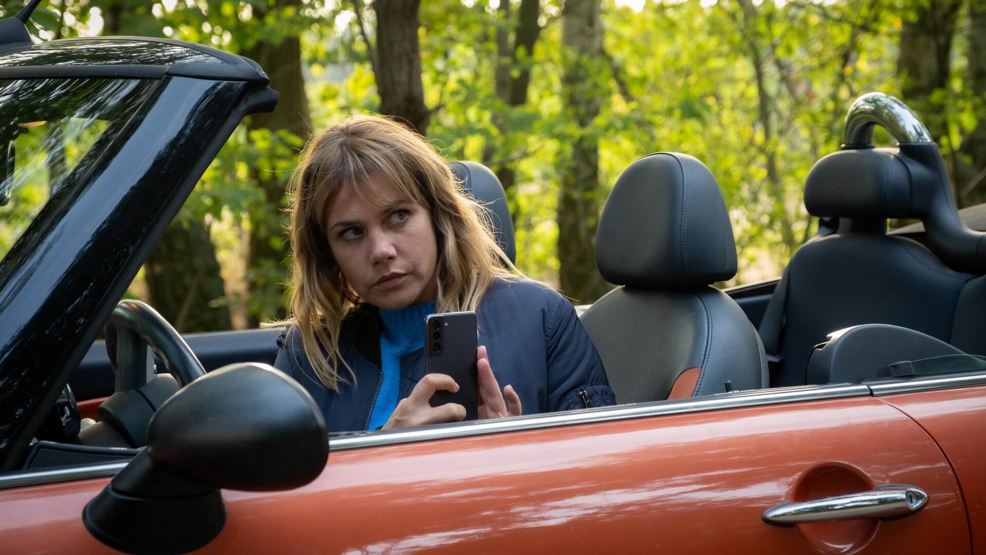 „Neuer Wind im Alten Land – Beke wirbelt auf“: Beke (Felicitas Woll) sitzt in ihrem offenen Cabrio und macht aus dem Auto heraus ein Bild mit ihrem Handy.