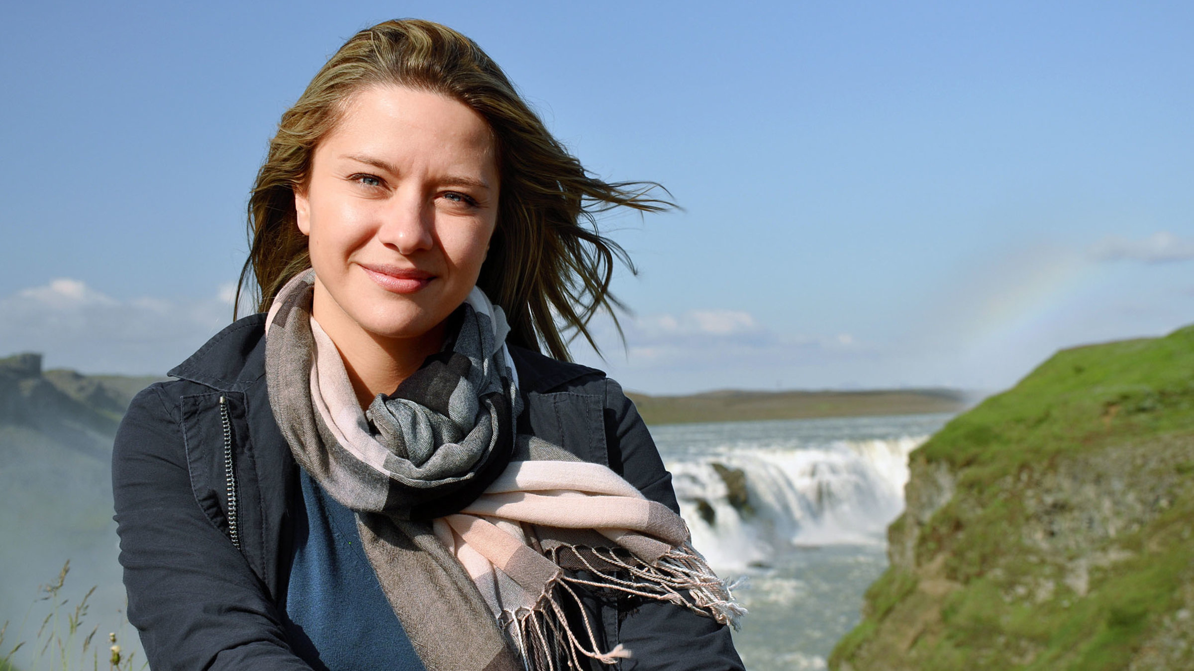 "unterwegs - Island": Moderatorin Wasiliki Goutziomitros in Island. Hinter ihr ist ein Wasserfall.