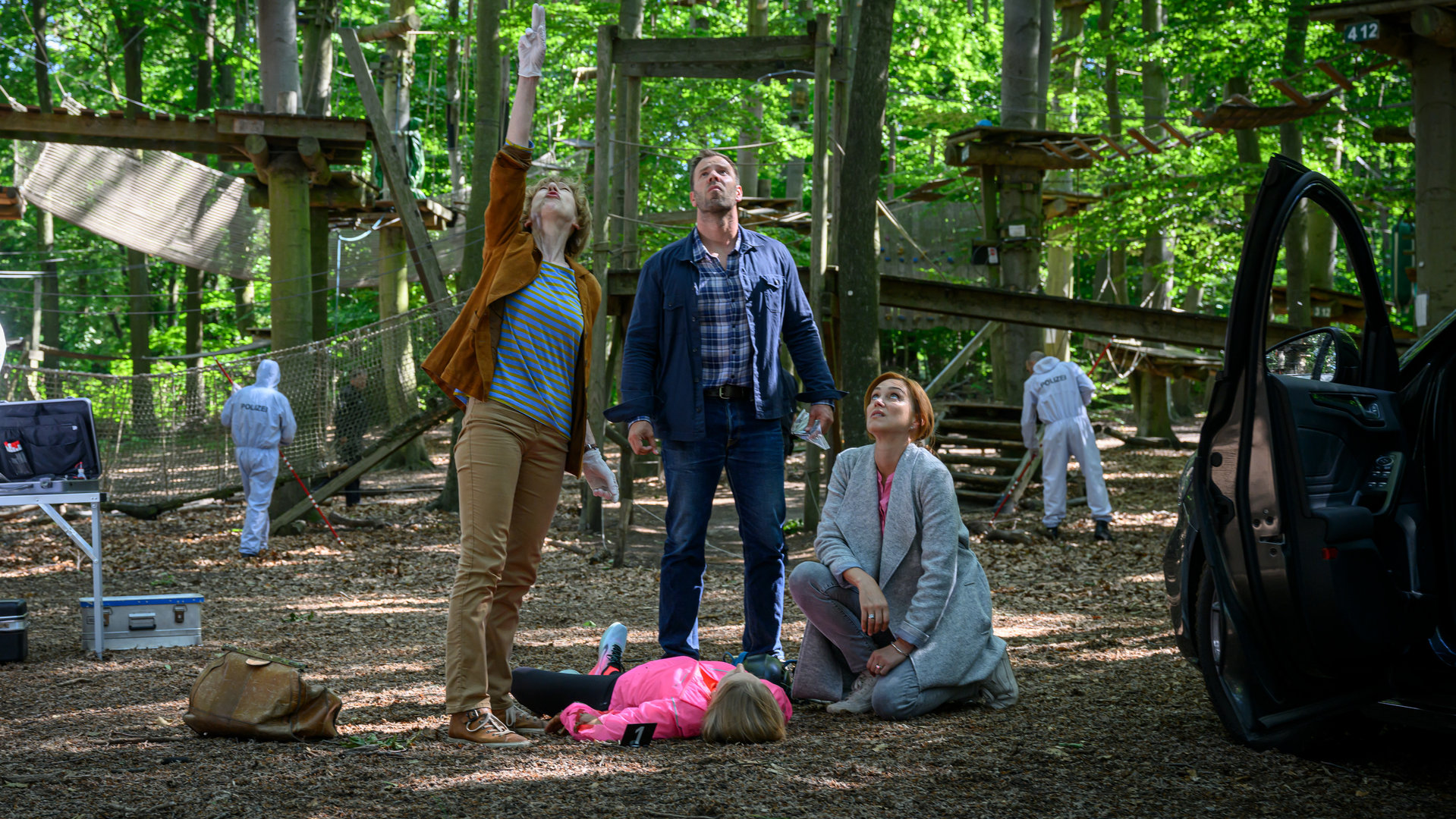"SOKO Wismar – Tiefer Fall": Das Opfer Antje Kölling (Kim Ruhnau) liegt im Kletterpark im Wald auf dem Boden. Das Ermittlungsteam, Dr. Helene Sturbeck (Katharina Blaschke), Lars Pöhlmann (Dominic Boeer) und Karoline Joost (Nike Fuhrmann) stehen um das Opfer herum und blicken nach oben zur Absturzstelle.