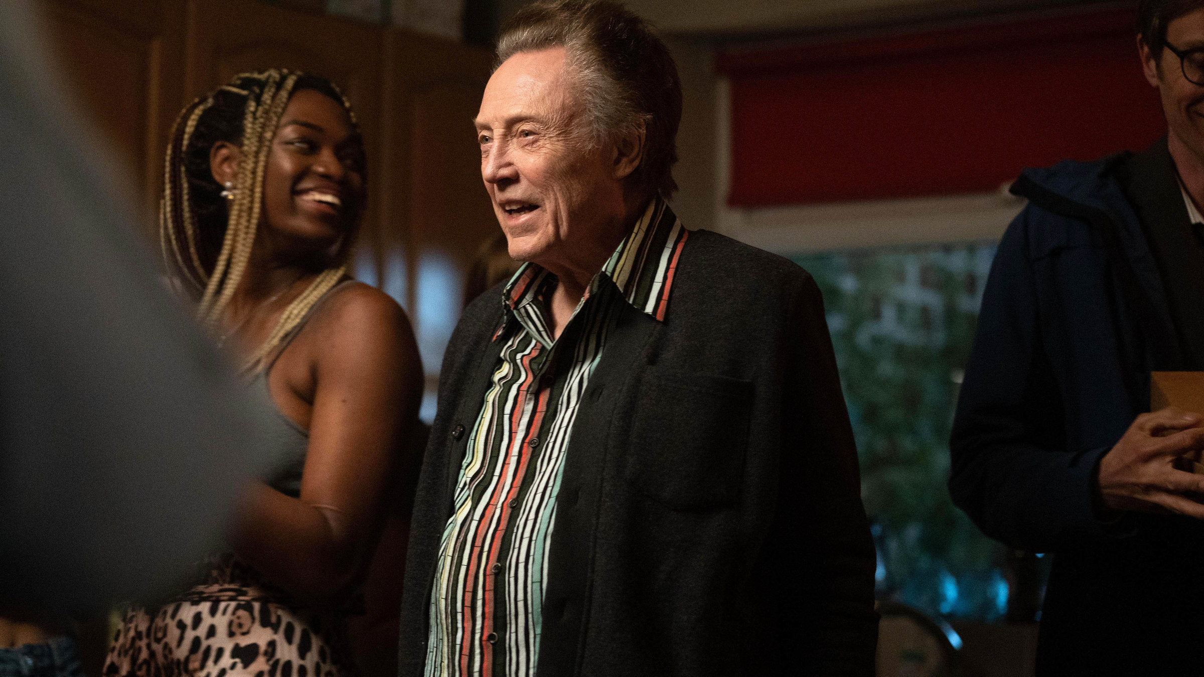 "The Outlaws - Eine Tasche voller Geld": Frank (Christopher Walken) steht in einer Wohnung inmitten einer Menge junger Leute und schaut lächelnd nach vorne.