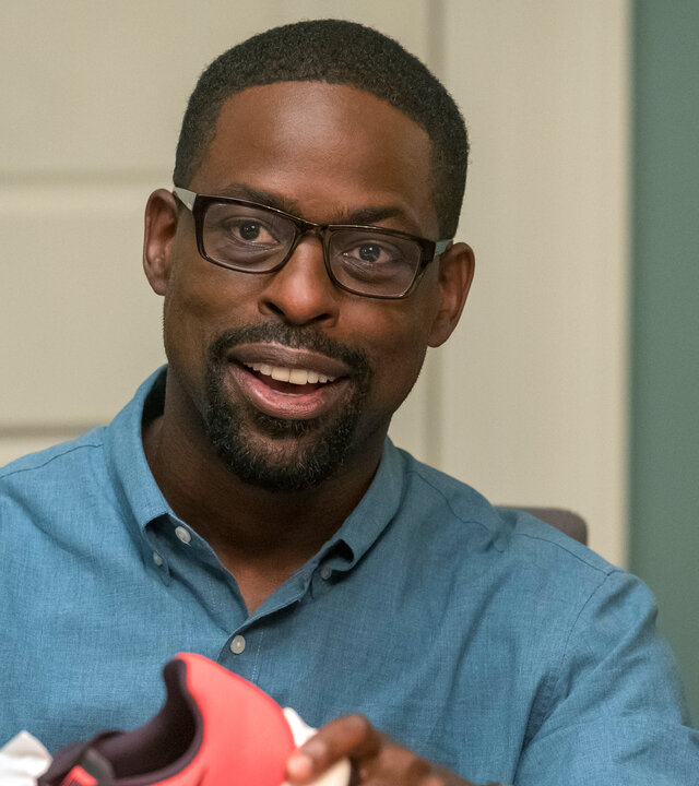 "This Is Us - Das ist Leben: Neun Dollar": Randall Pearson (Sterling K. Brown) sitzt an einem Tisch und packt Turnschuhe aus einem Schuhkarton aus. Er blickt lächelnd nach vorn.